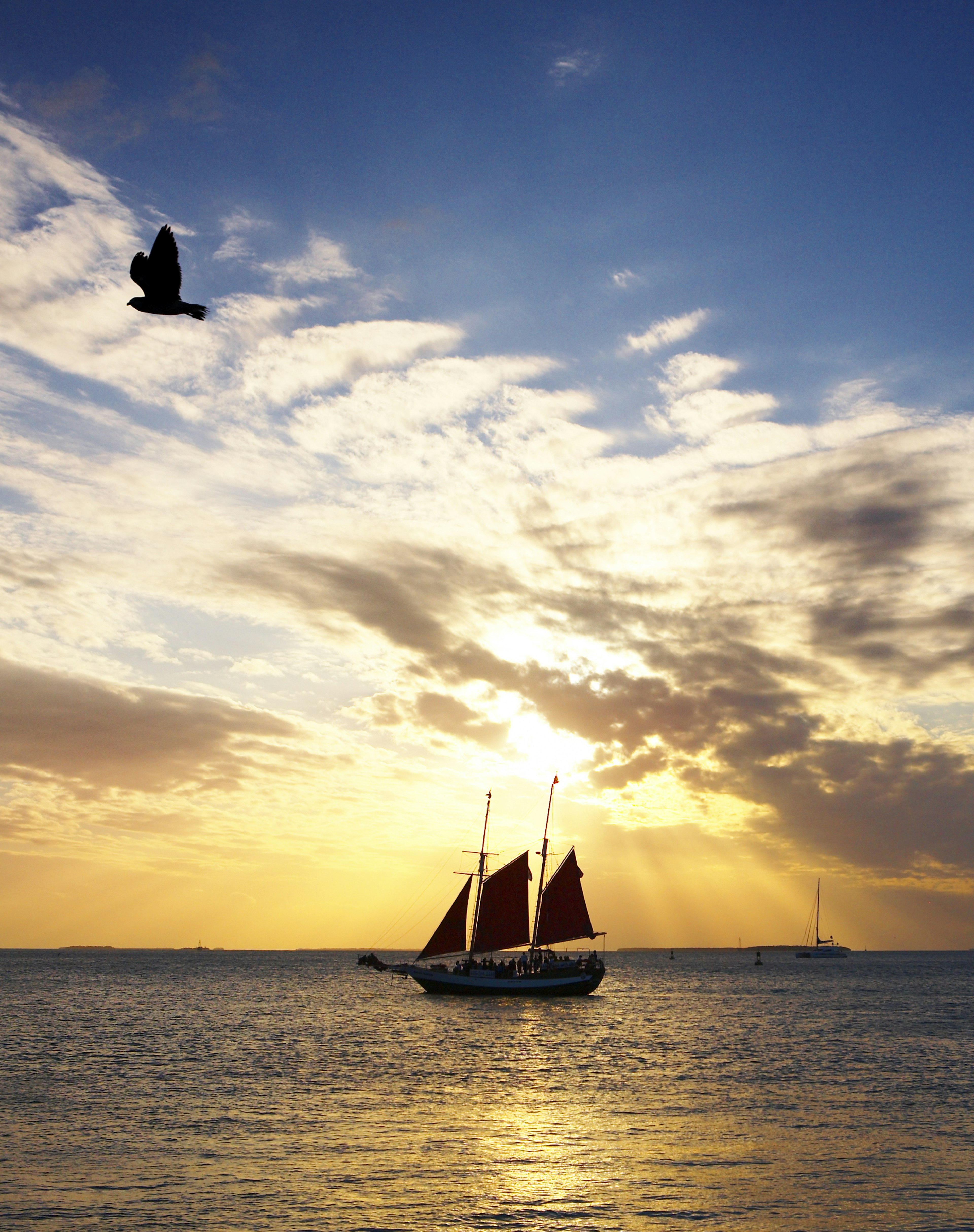 A yacht is silhouetted against a striking orange sunset