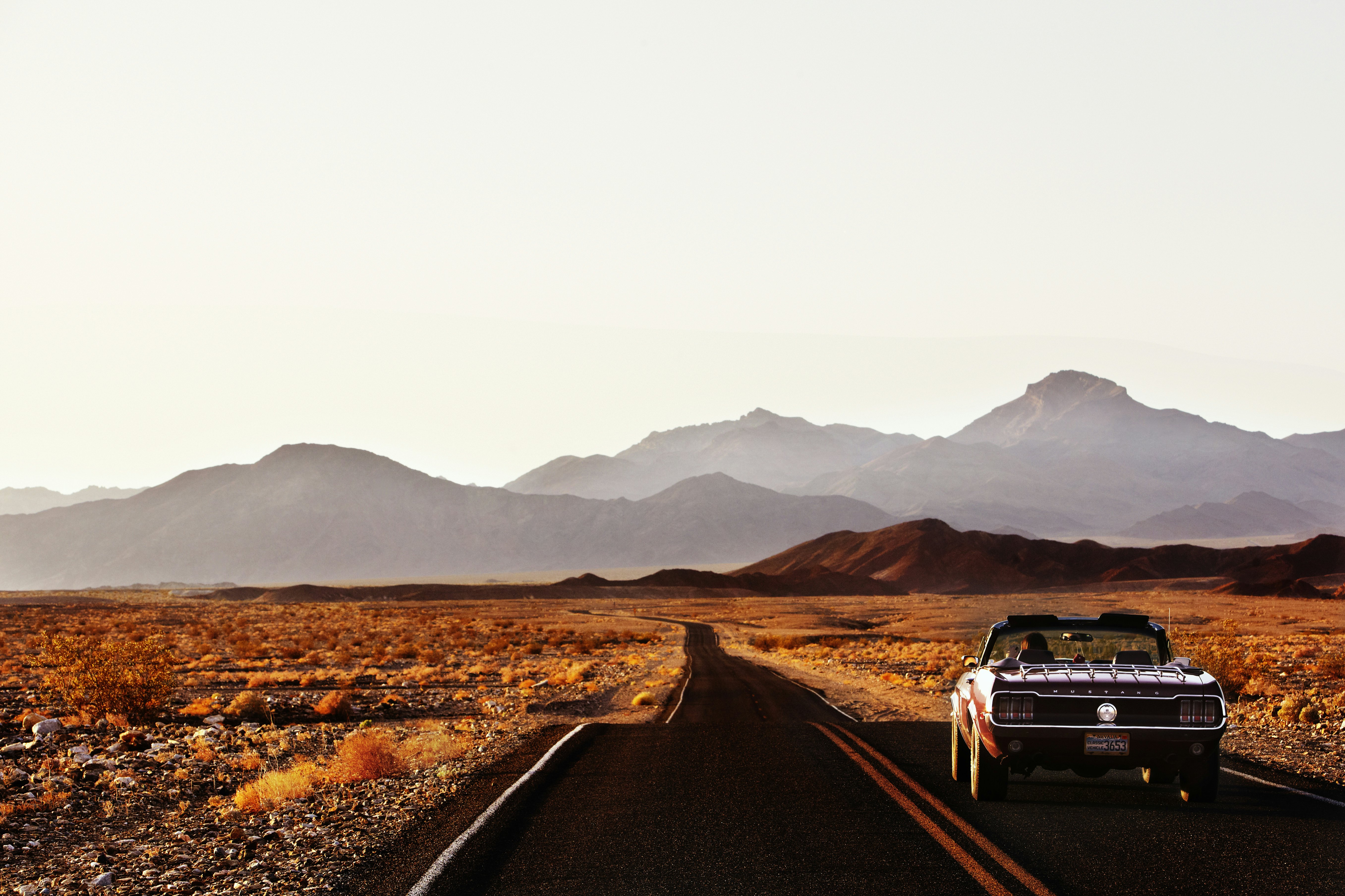 A car driving down a road through the desert landscape of Death Valley.