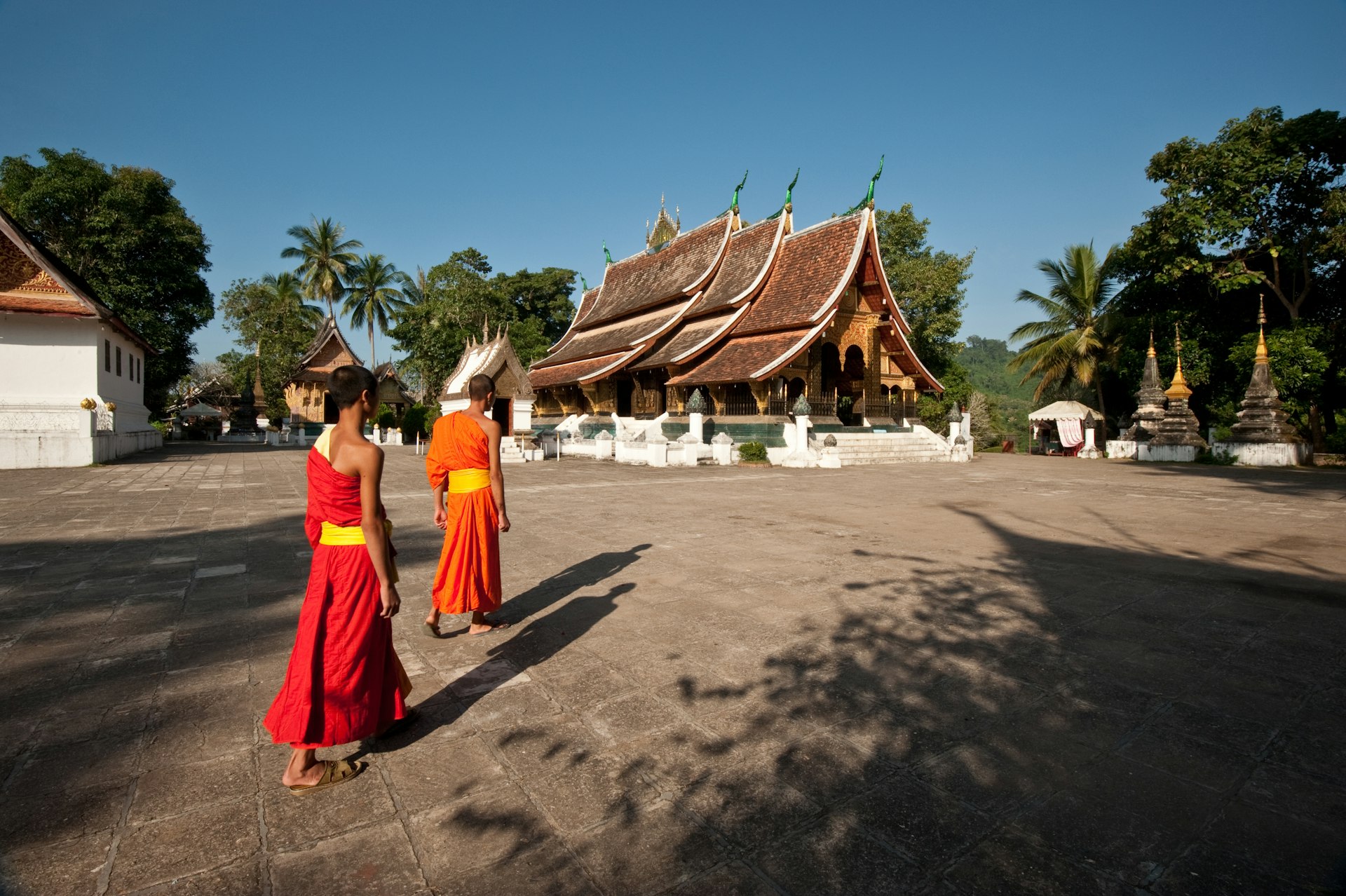 Two novice monks walking the grounds of Wat Xieng Thong temple, Luang Prabang, Laos