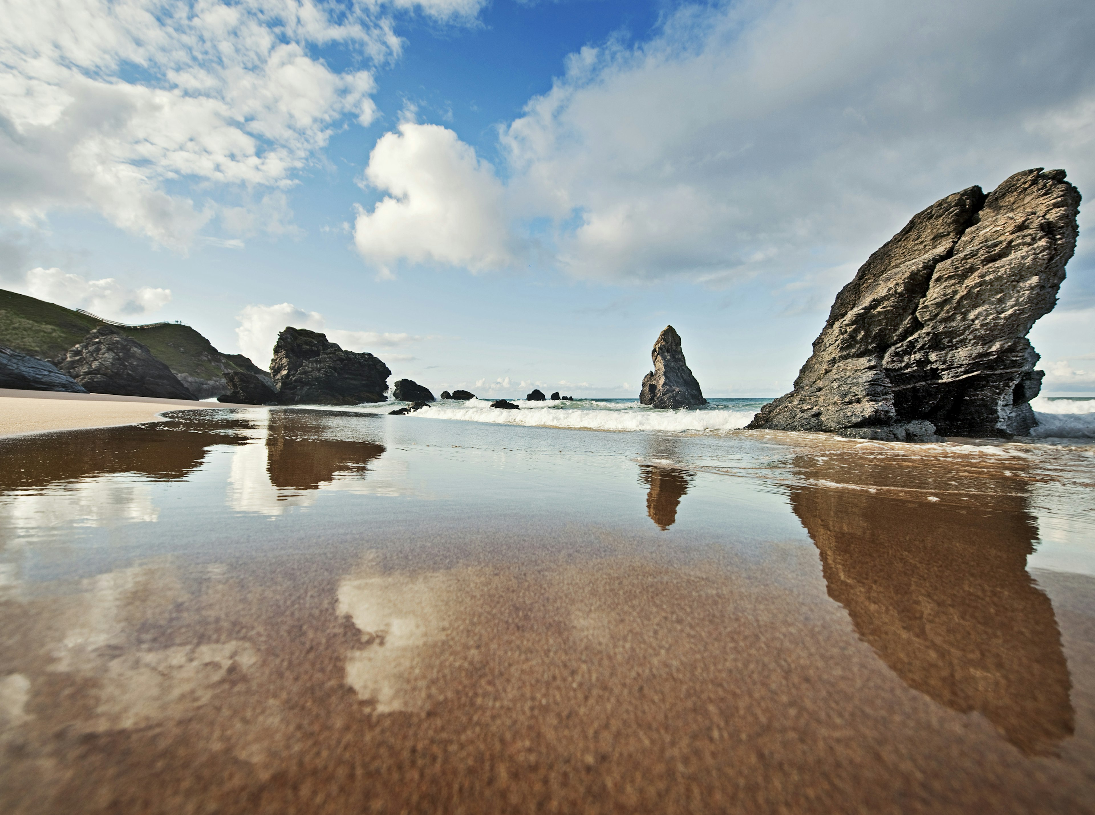 A bay of clear sea water with several tall rocky outcrops