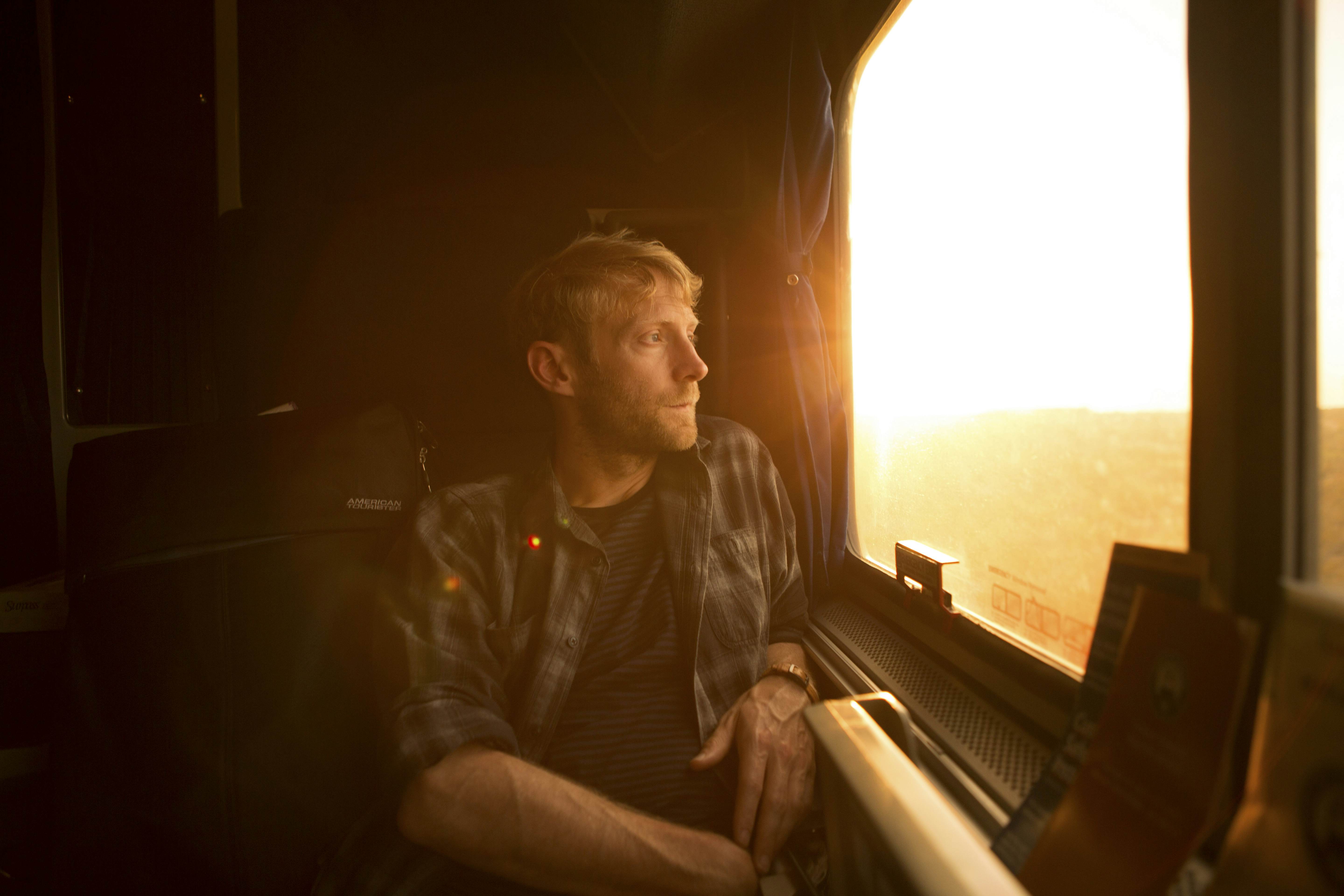 A train passenger seated by a window at sunset