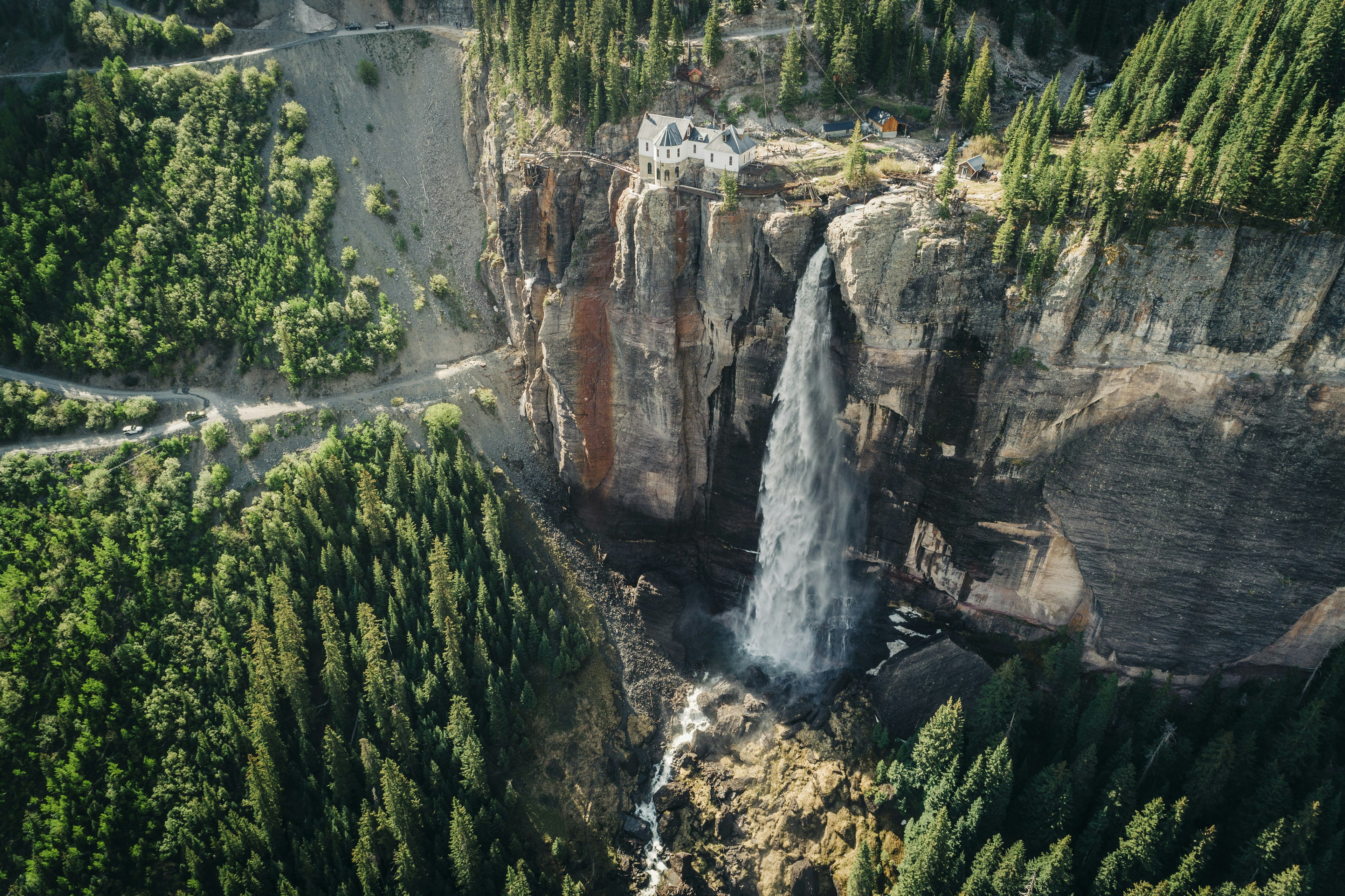 A waterfall cascades down into a forested canyon