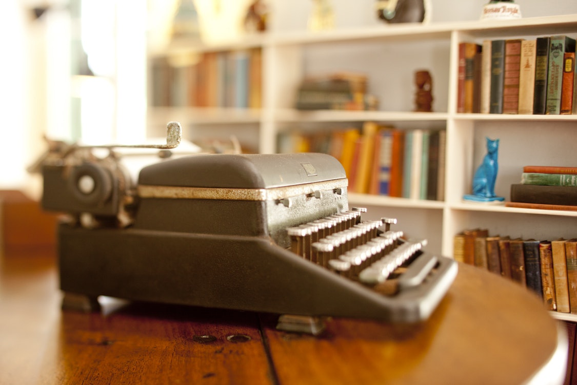 An antique typewriter sits on a table in an office in a historic home.