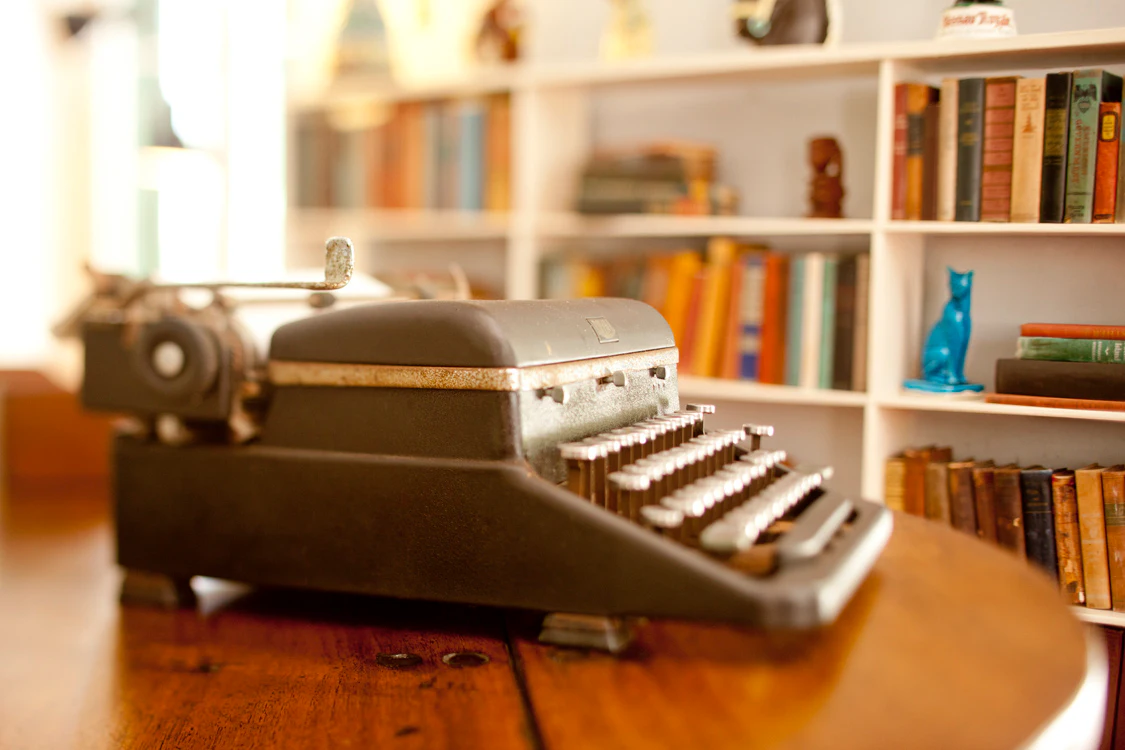 An antique typewriter sits on a table in an office in a historic home.