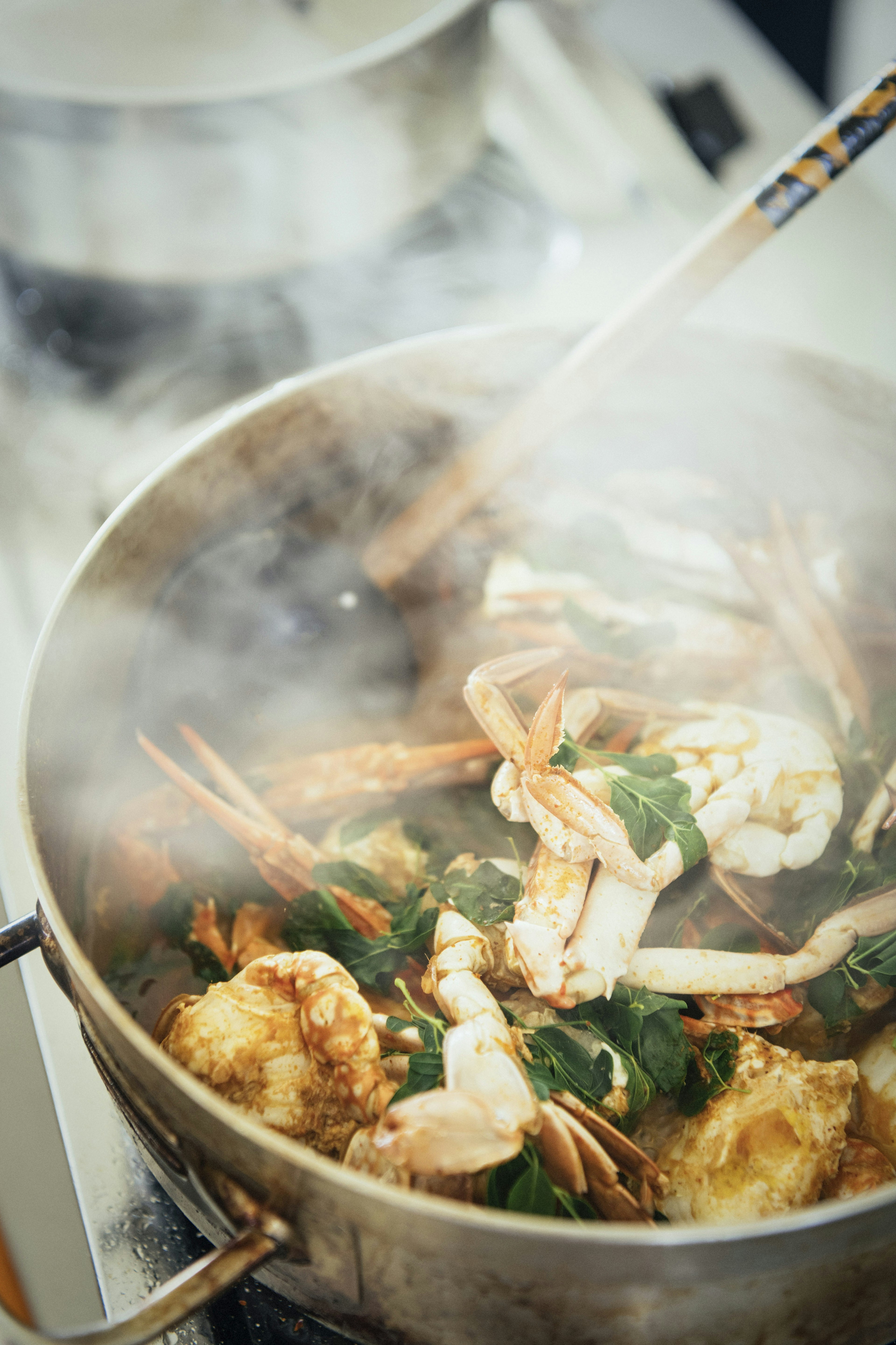 A pot of Jaffna crab curry, with a few murunga leaves on it.