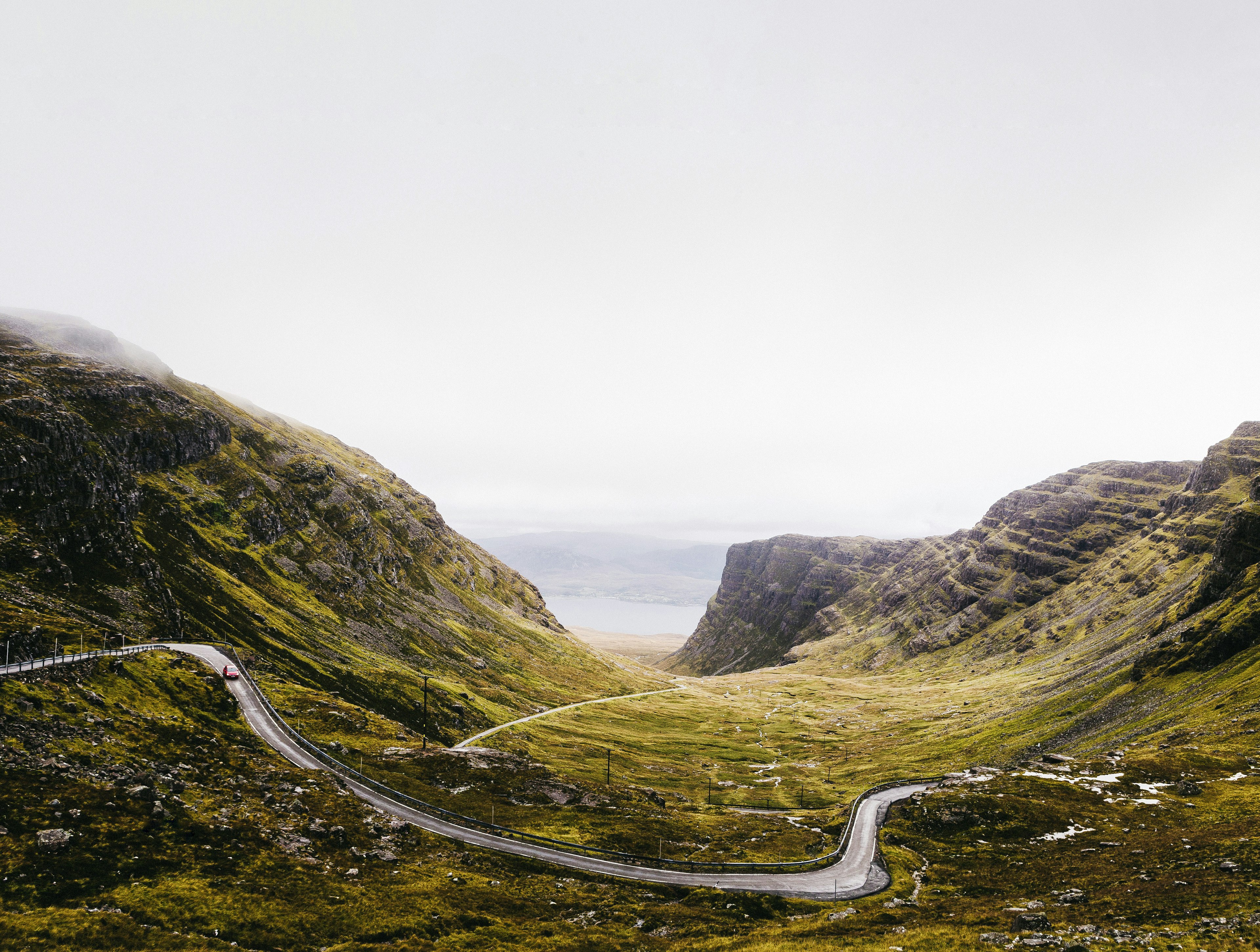 A hugely winding road weaves through hilly landscape on a foggy day