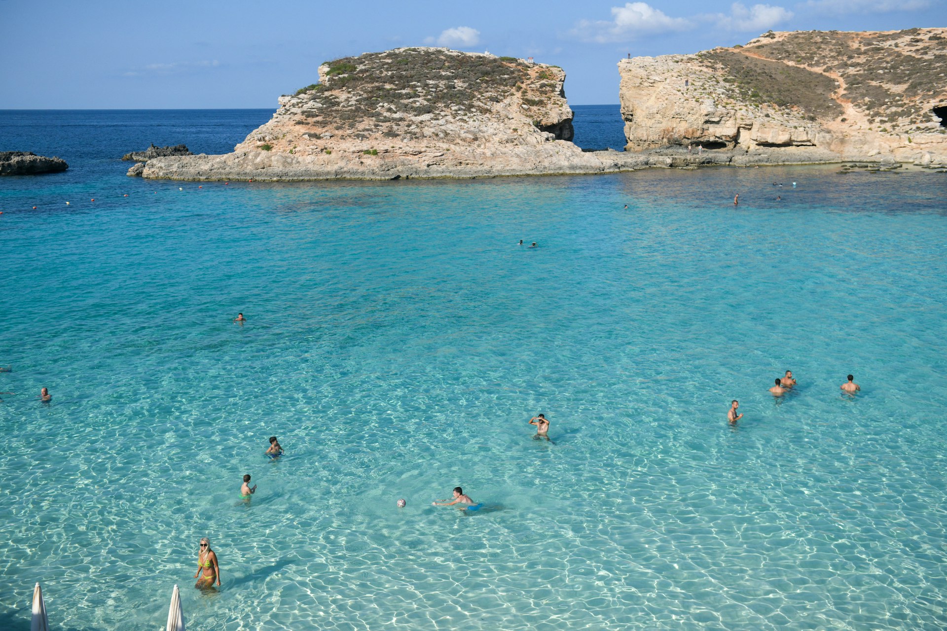 People swim in the bright blue waters of Malta's Blue Lagoon. 