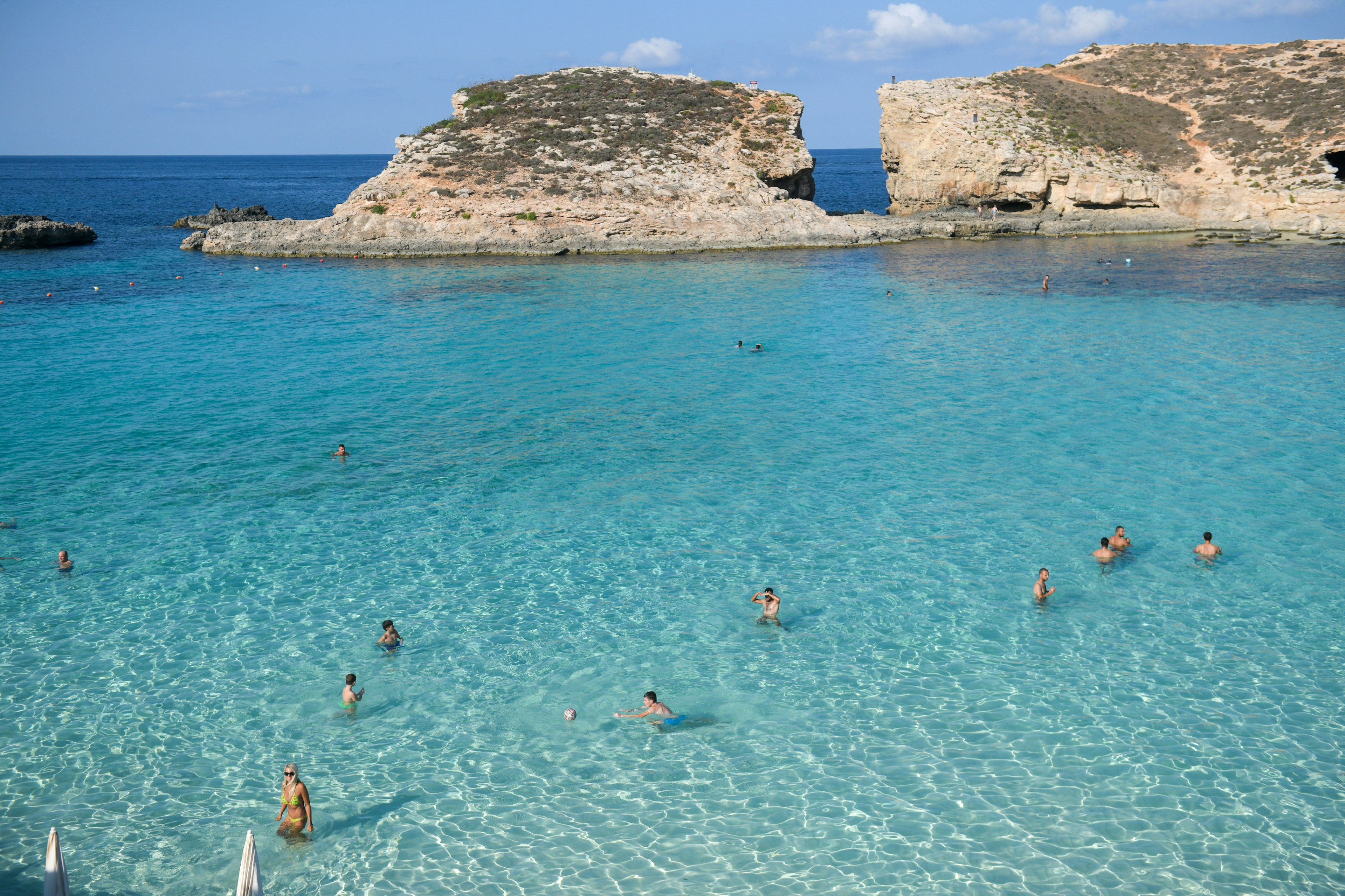 People swim in the bright blue waters of Malta's Blue Lagoon.