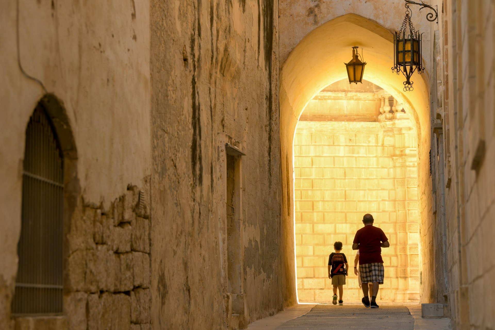 Silhouettes of people walking in the old streets of Mdina, Malta.