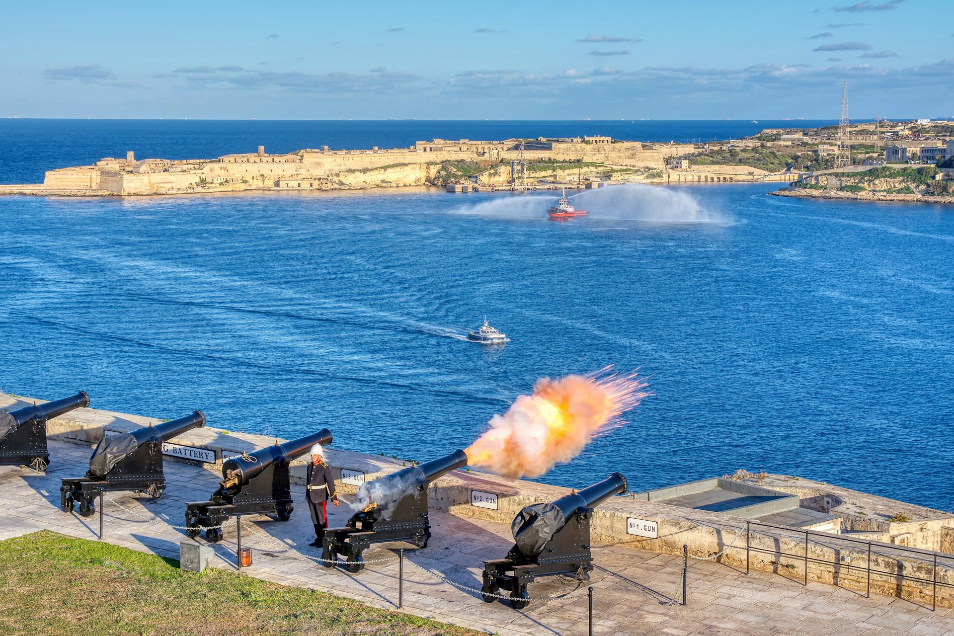 A cannon fires at noon from the Saluting Battery in Valletta, Malta, with Birgu on the background. 