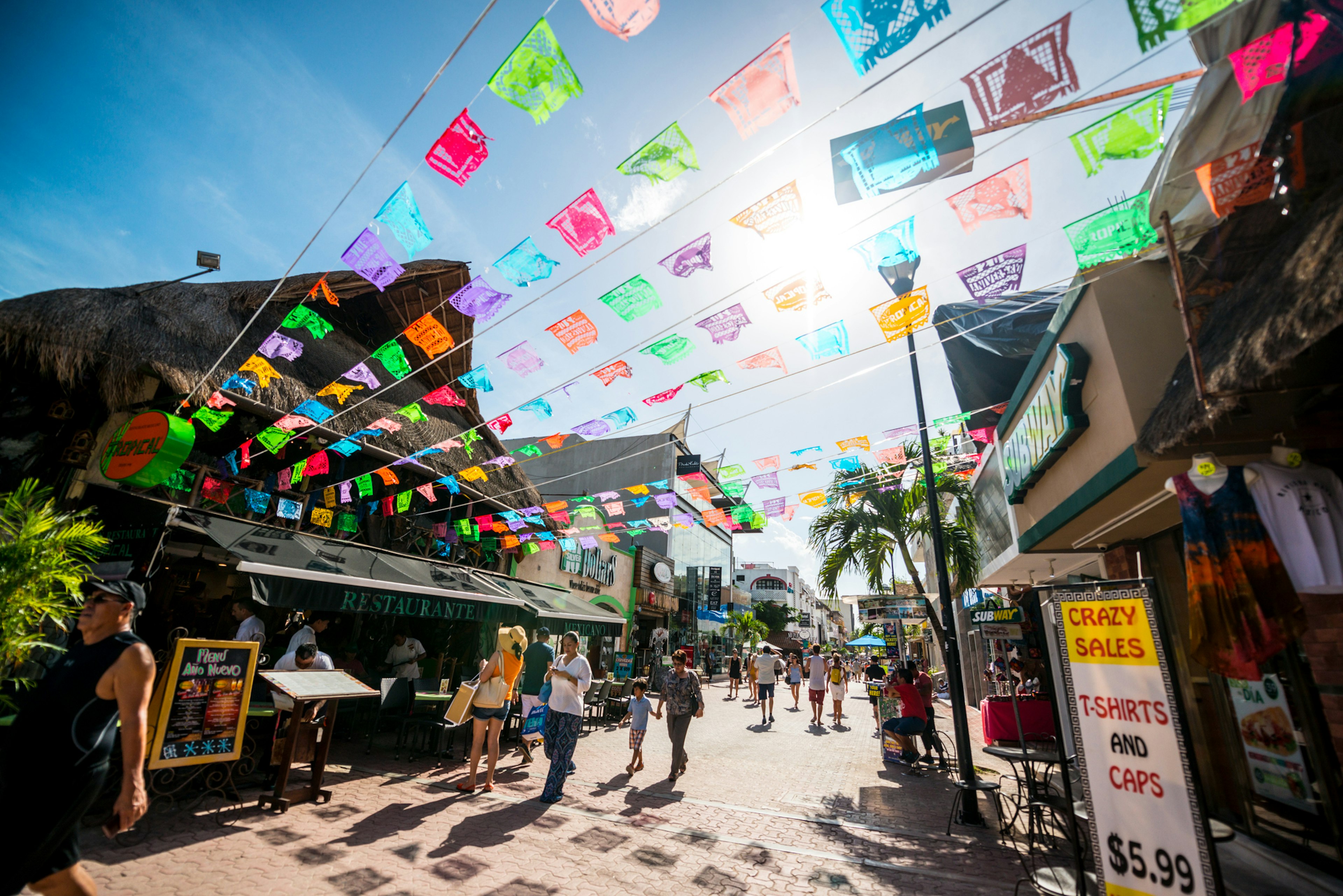 Tourists exploring a predestrianized shopping street with colorful bunting fluttering in the breeze