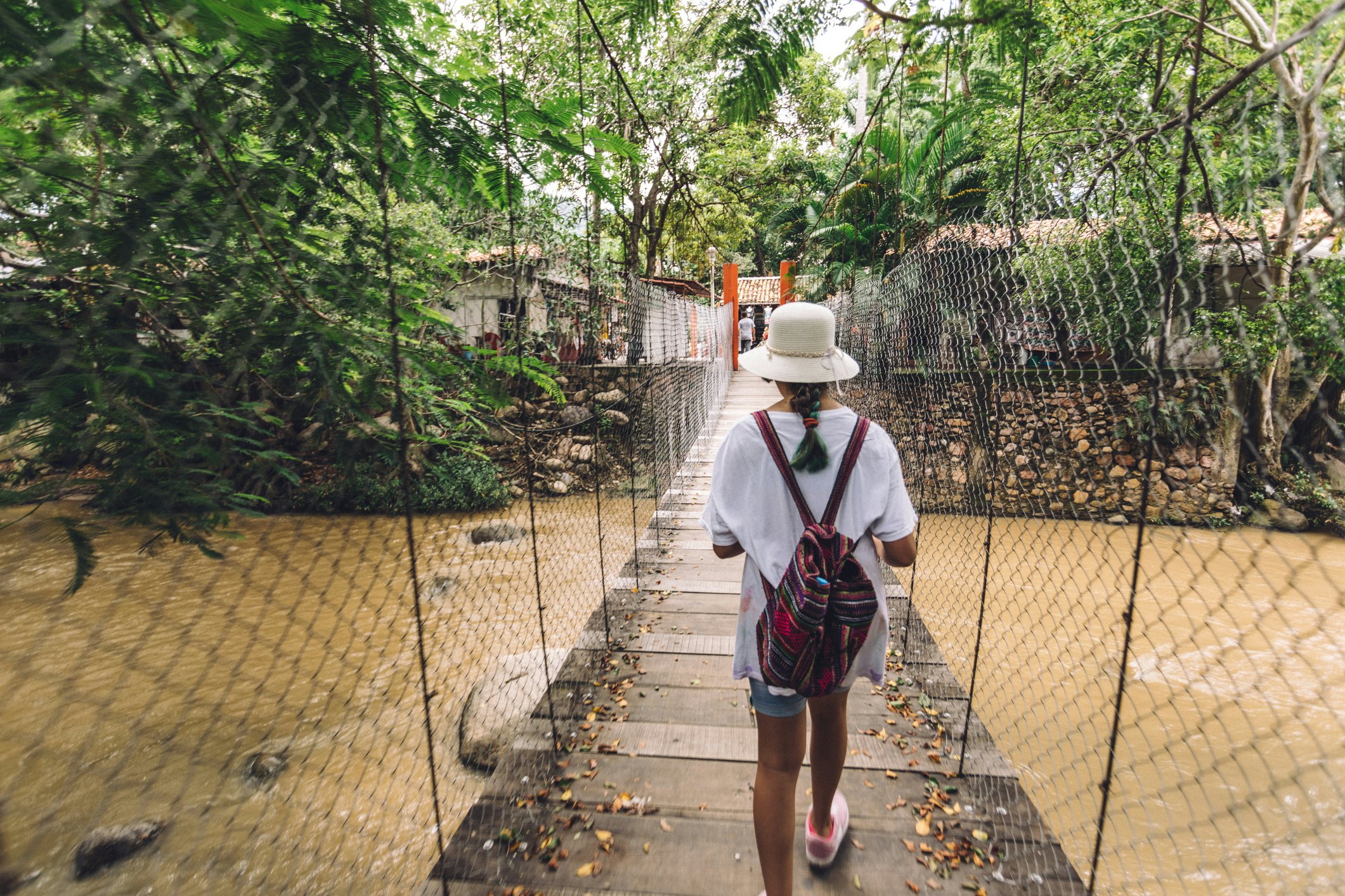 A teenager crossing a suspended bridge towards Isla Rio Cuale at Puerto Vallarta.