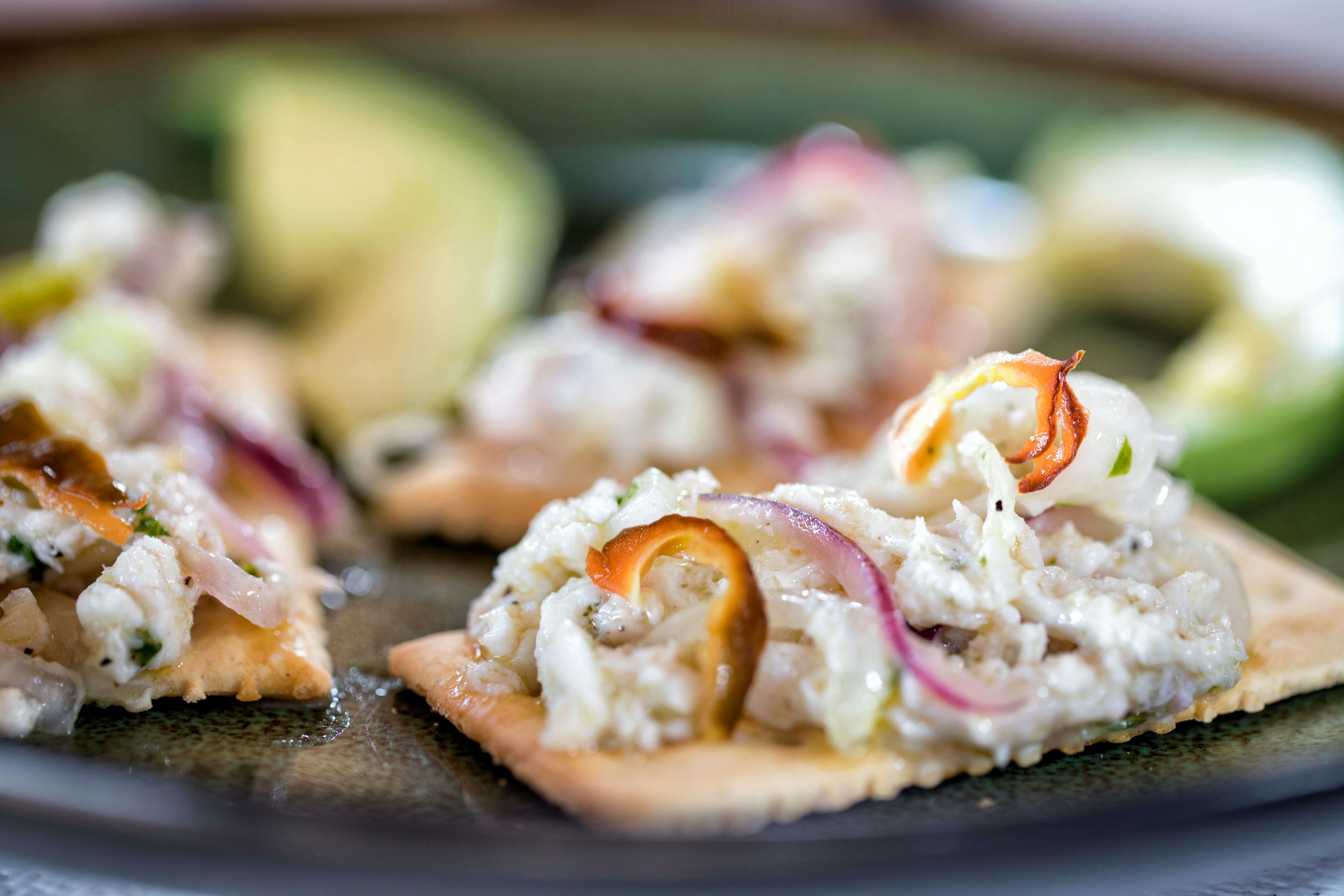 Marinated fish strips topped with thin-sliced onions and chiles, served on a cracker