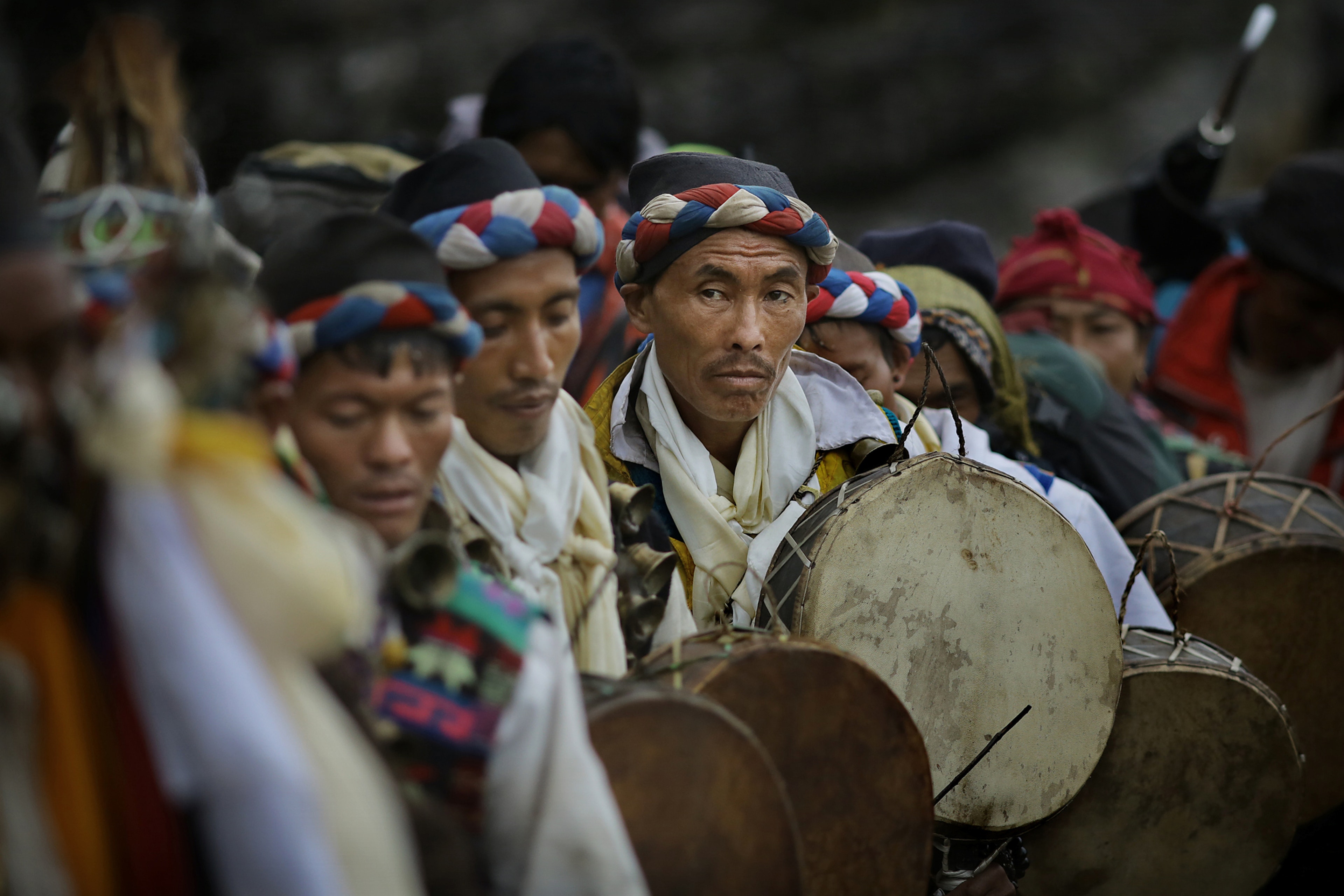 Indigenous Tamang shamans stand in a line holding dhyangro drums during a ritual. Every year at August full moon thousands of Hindu pilgrims and Jhankri shamans trek up to Gosaikunda Lake 4380m-high in the Himalaya mountains to bathe in its cleansing waters and participate in indigenous rituals.