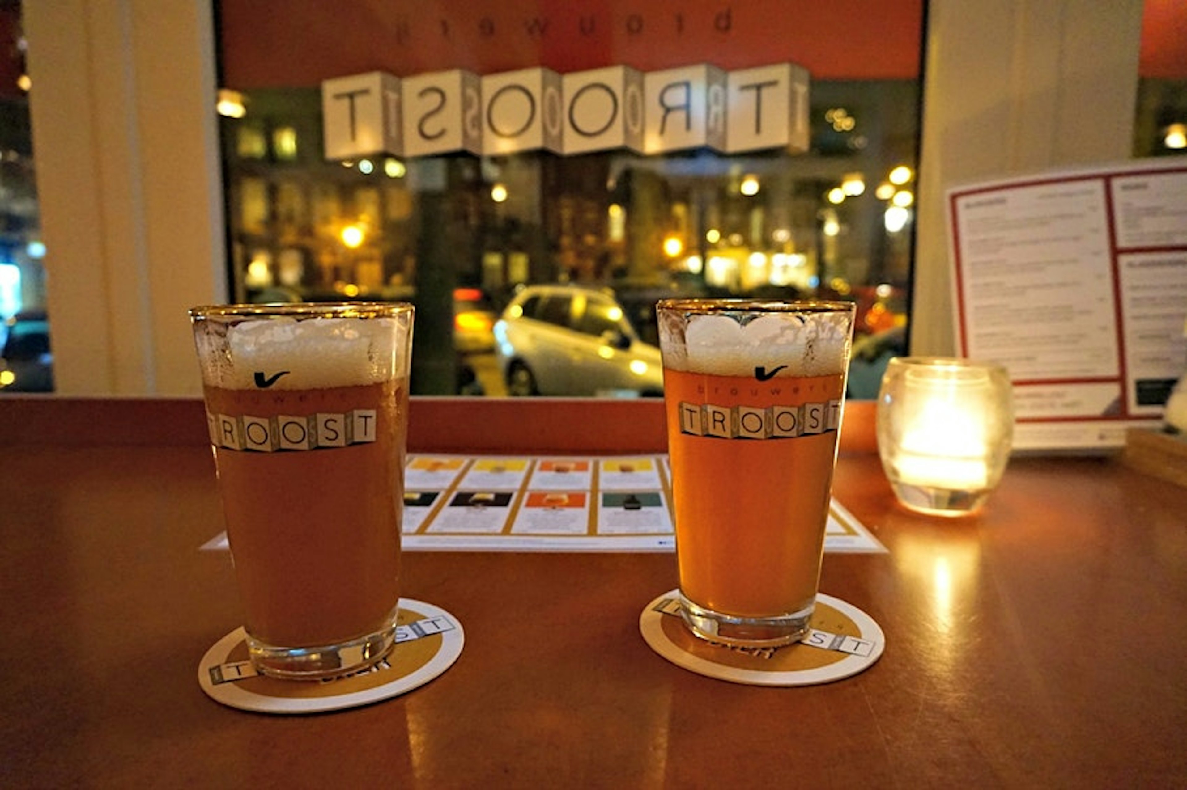 Two pints of beer are illuminated by a candlelight during an evening at Brouwerij Troost