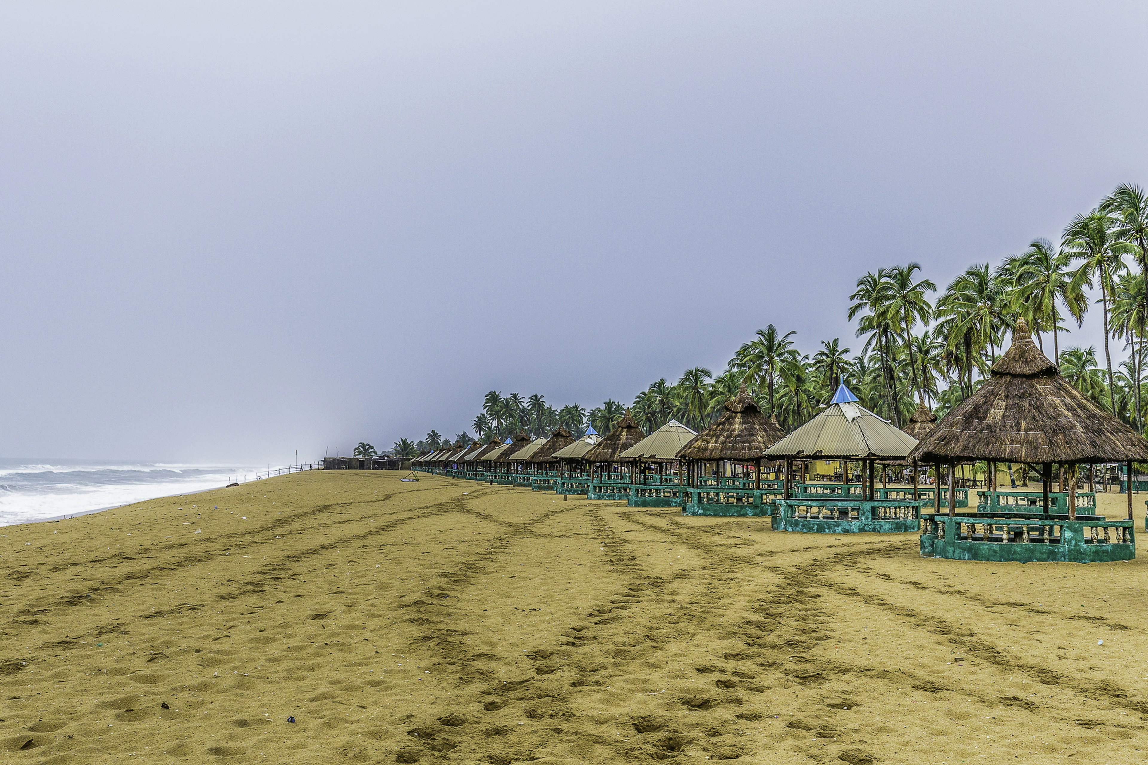 A long golden sand beach lined with beach huts stretches out into the distance