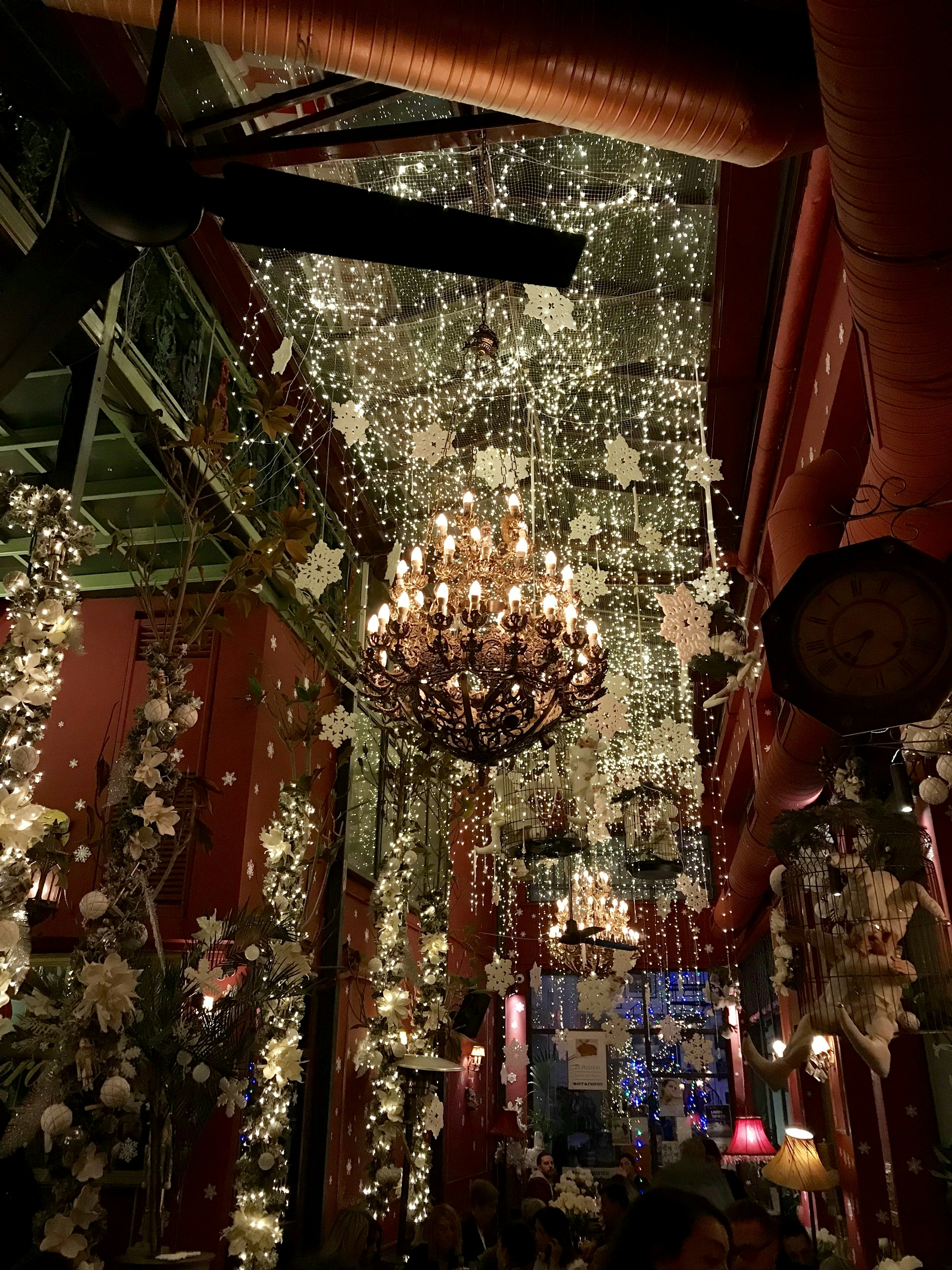 A large chandelier is covered in fake snow flakes that also hang from the ceilings at Noel Bar in Athens