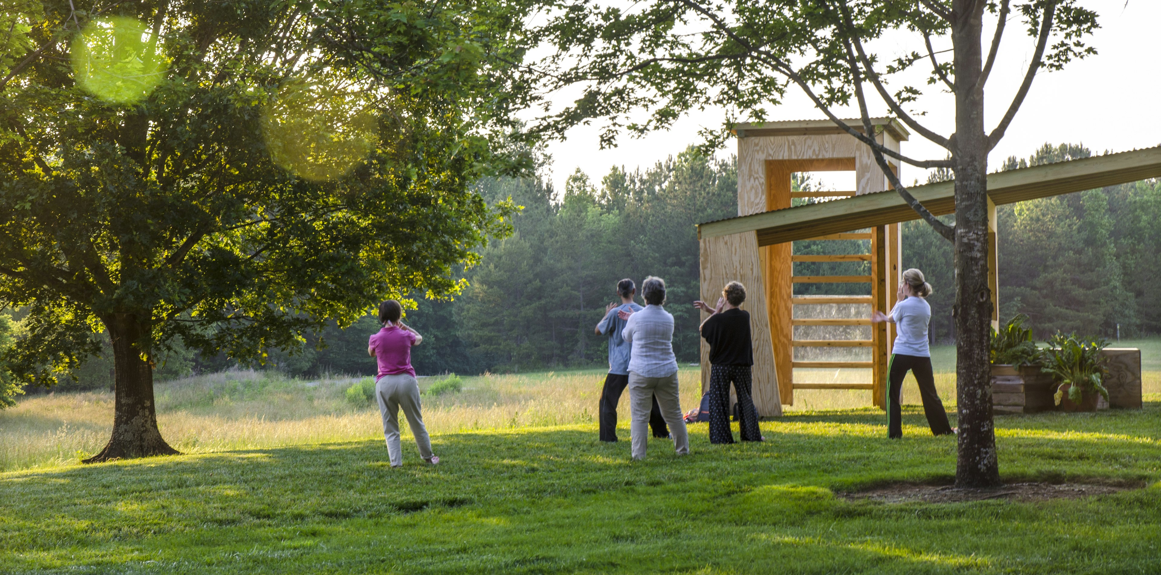 An instructor is teaching and performing Tai Chi to senior women at a Park as the sun sets in Belmont, NC.