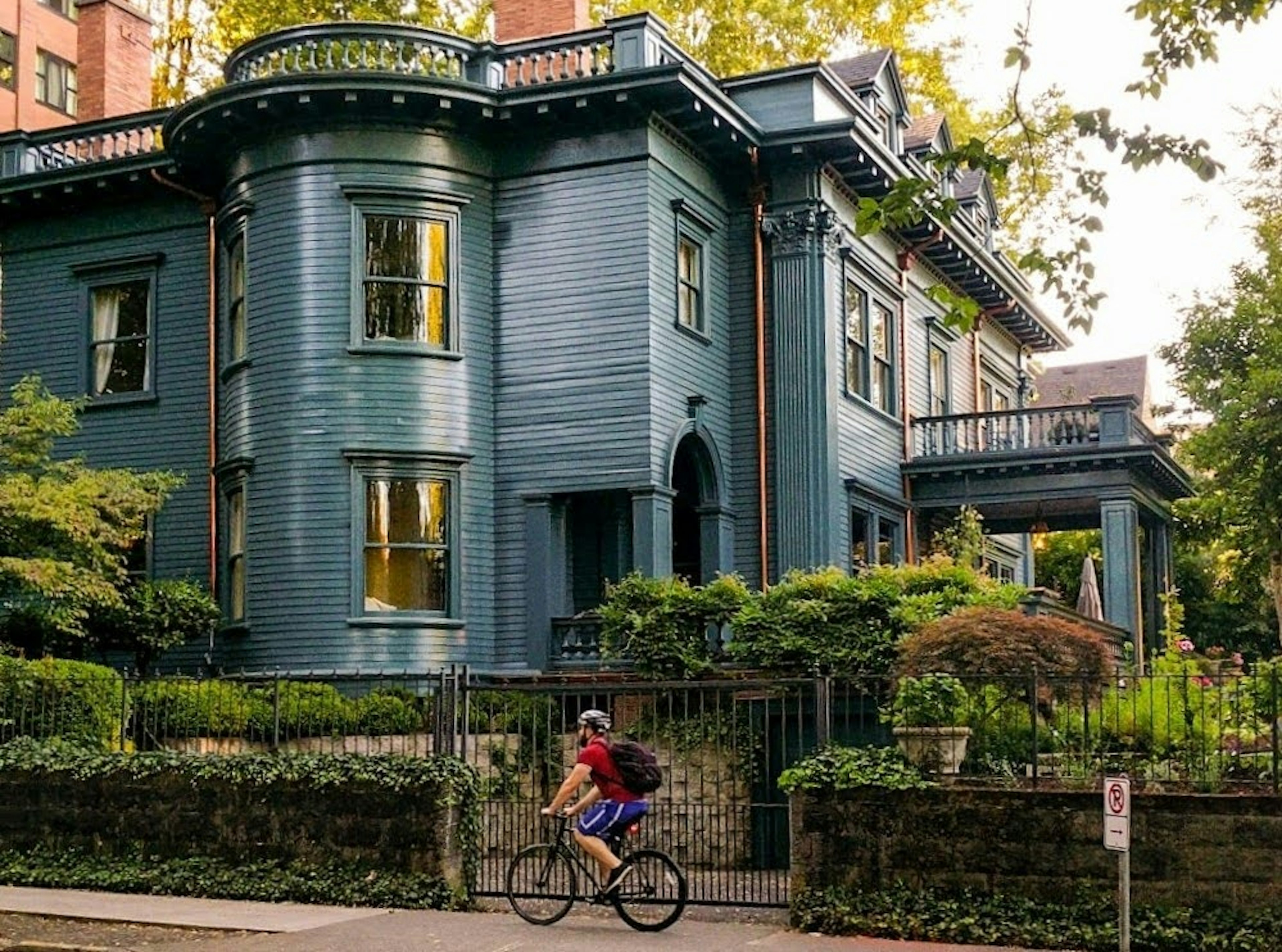 A cyclist in front of a stately turn-of-the-century home in the Alphabet District of Portland, Oregon