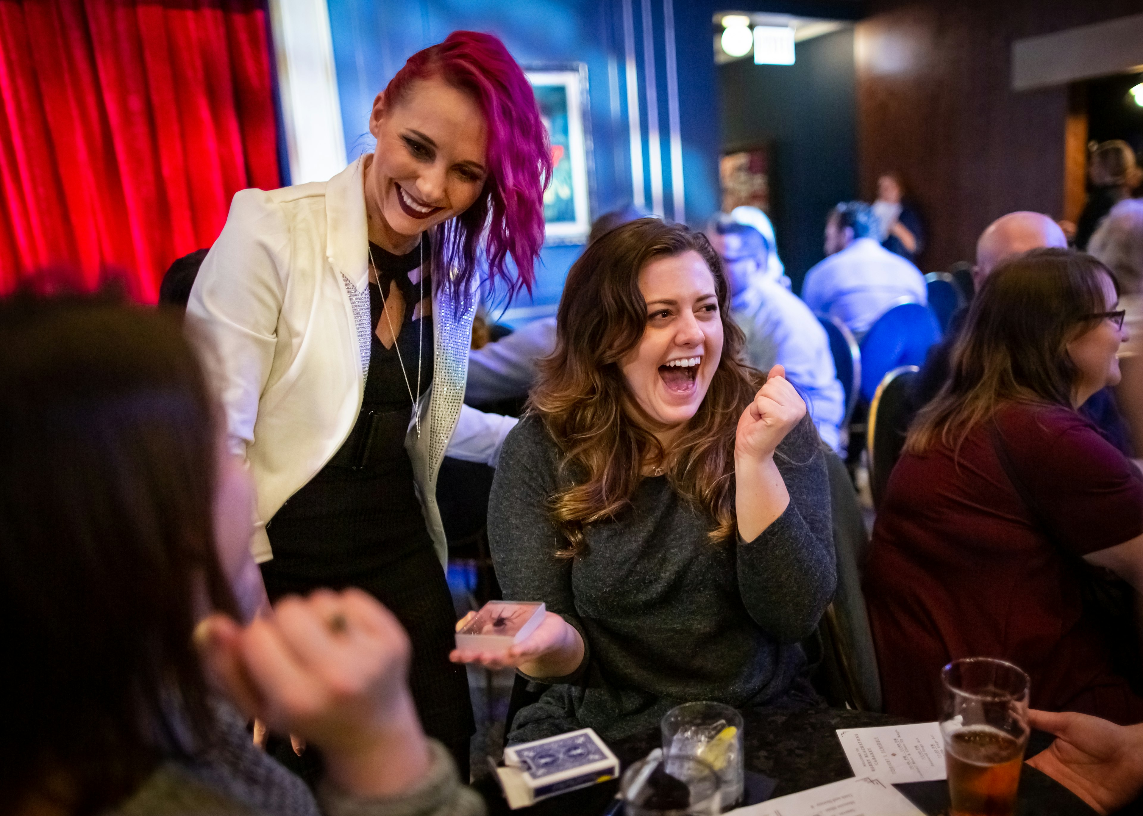 Magician Paige Thompson performs magic for guests seated at a table at Chicago Magic Lounge.