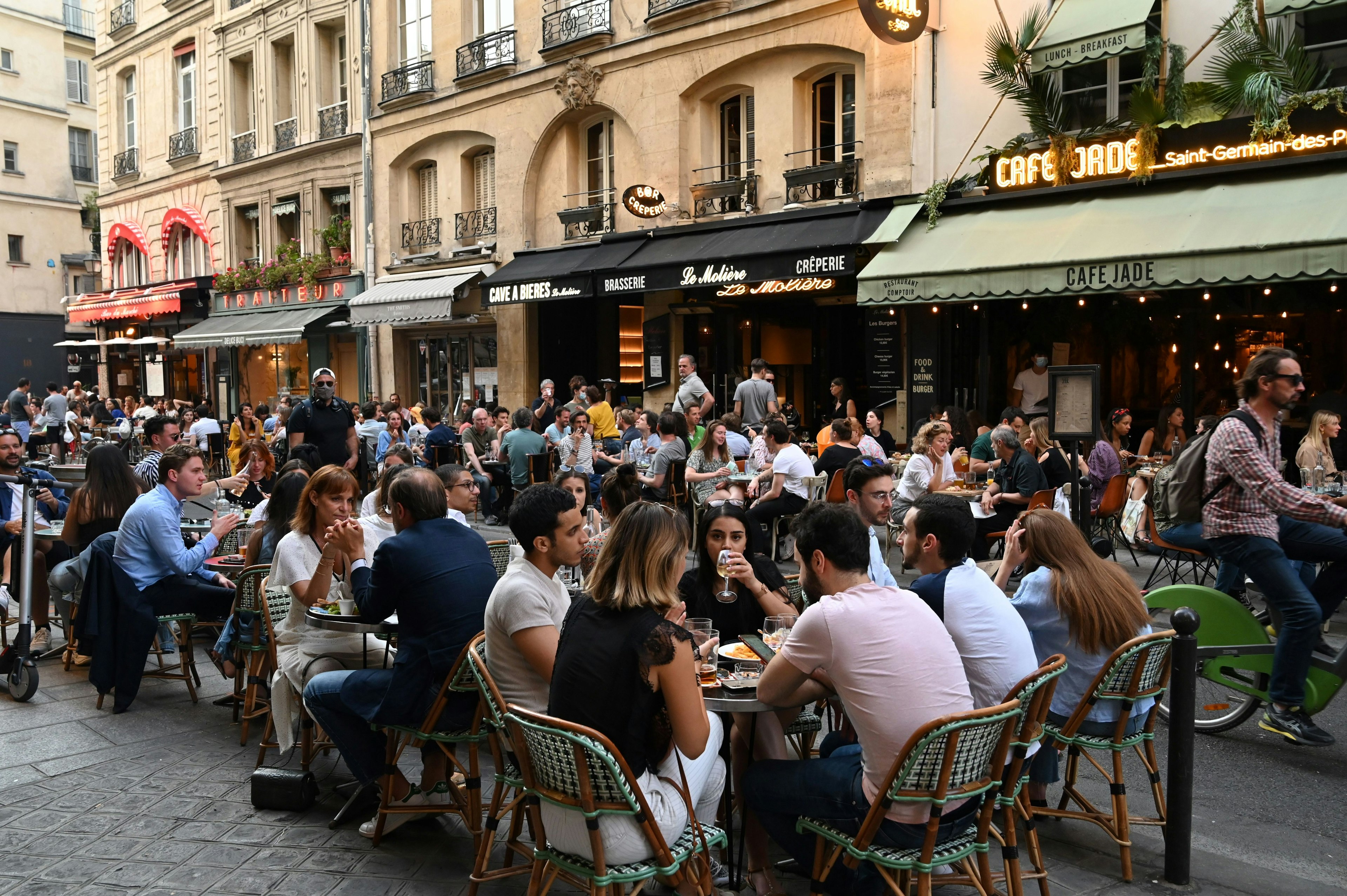 People eat and have drinks on restaurant and cafe terraces in Rue de Buci in Paris