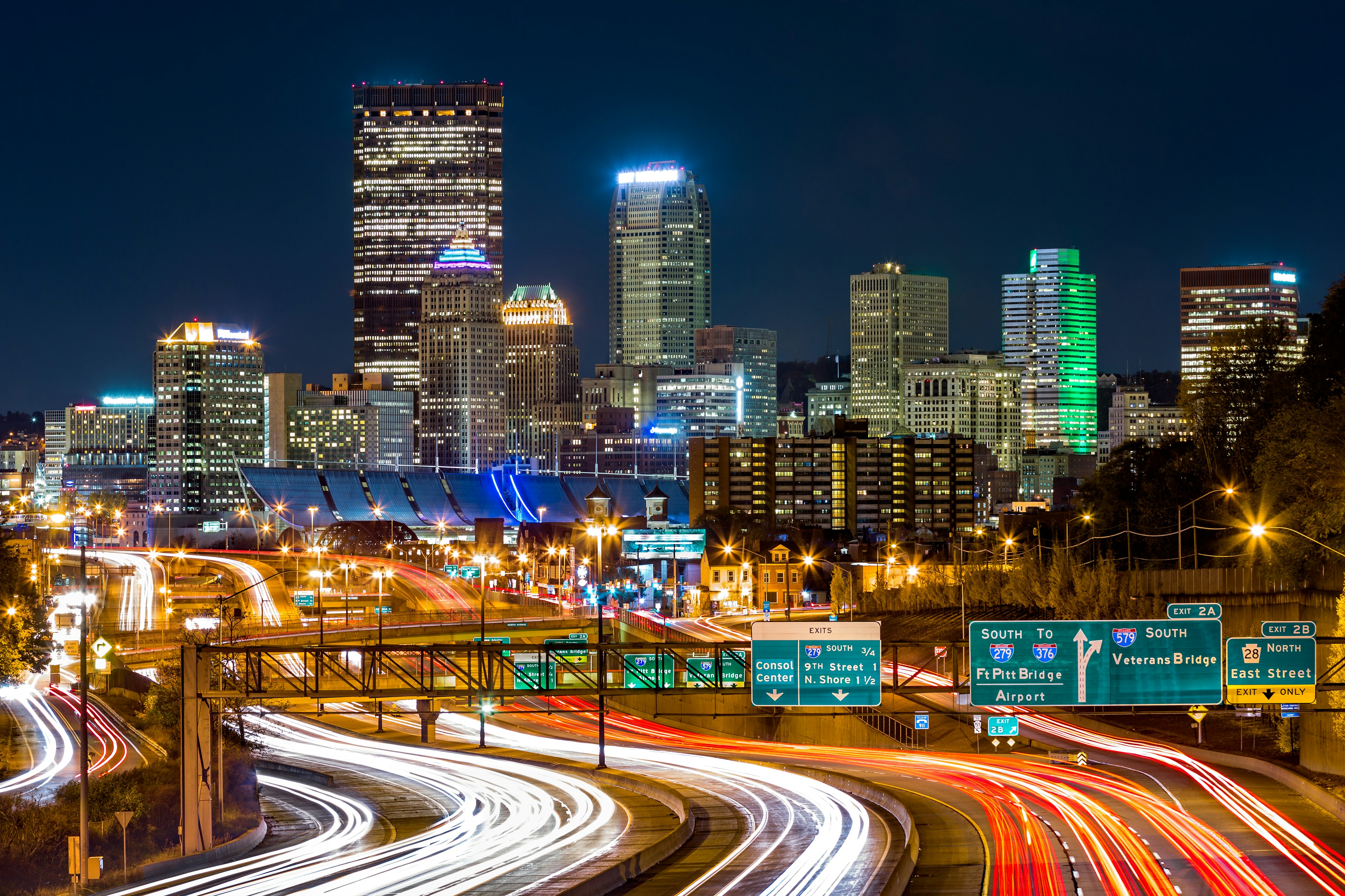 The Pittsburgh skyline by night, you can see the bright lights of cars driving on I-279 parkway