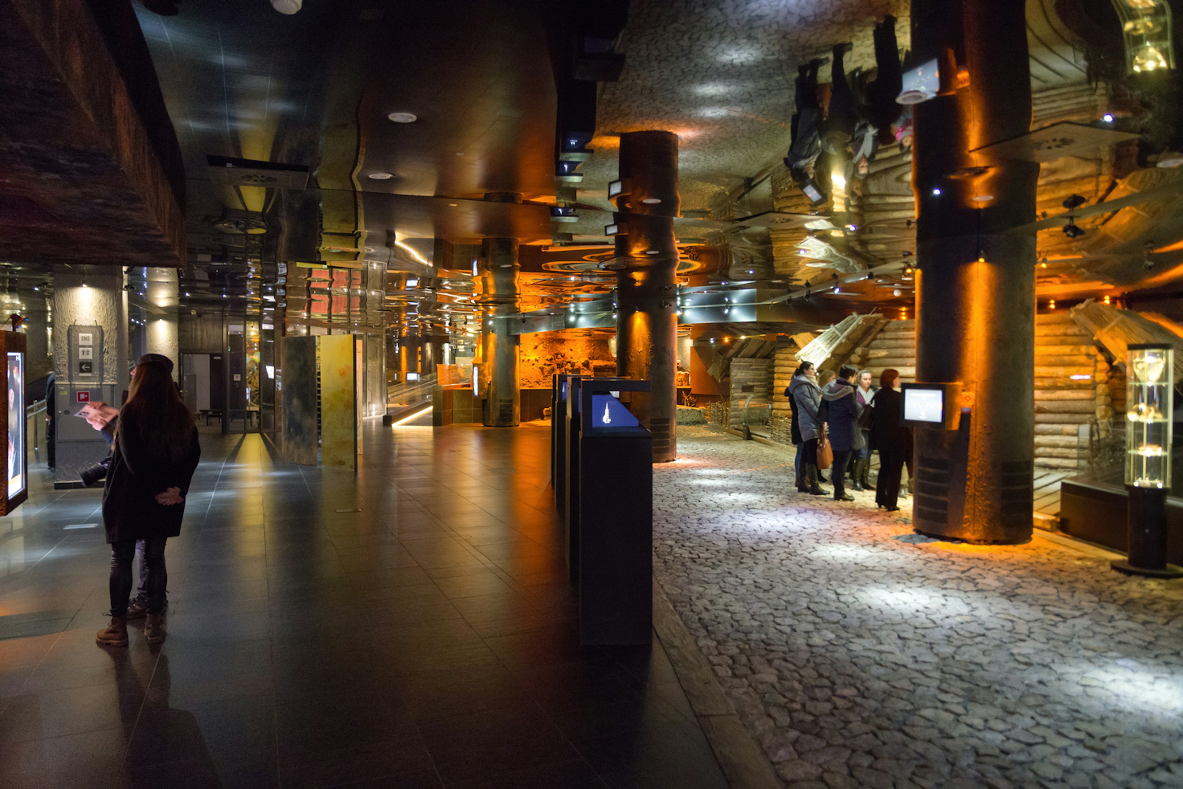 An underground archaeology museum with people looking at the darkened displays