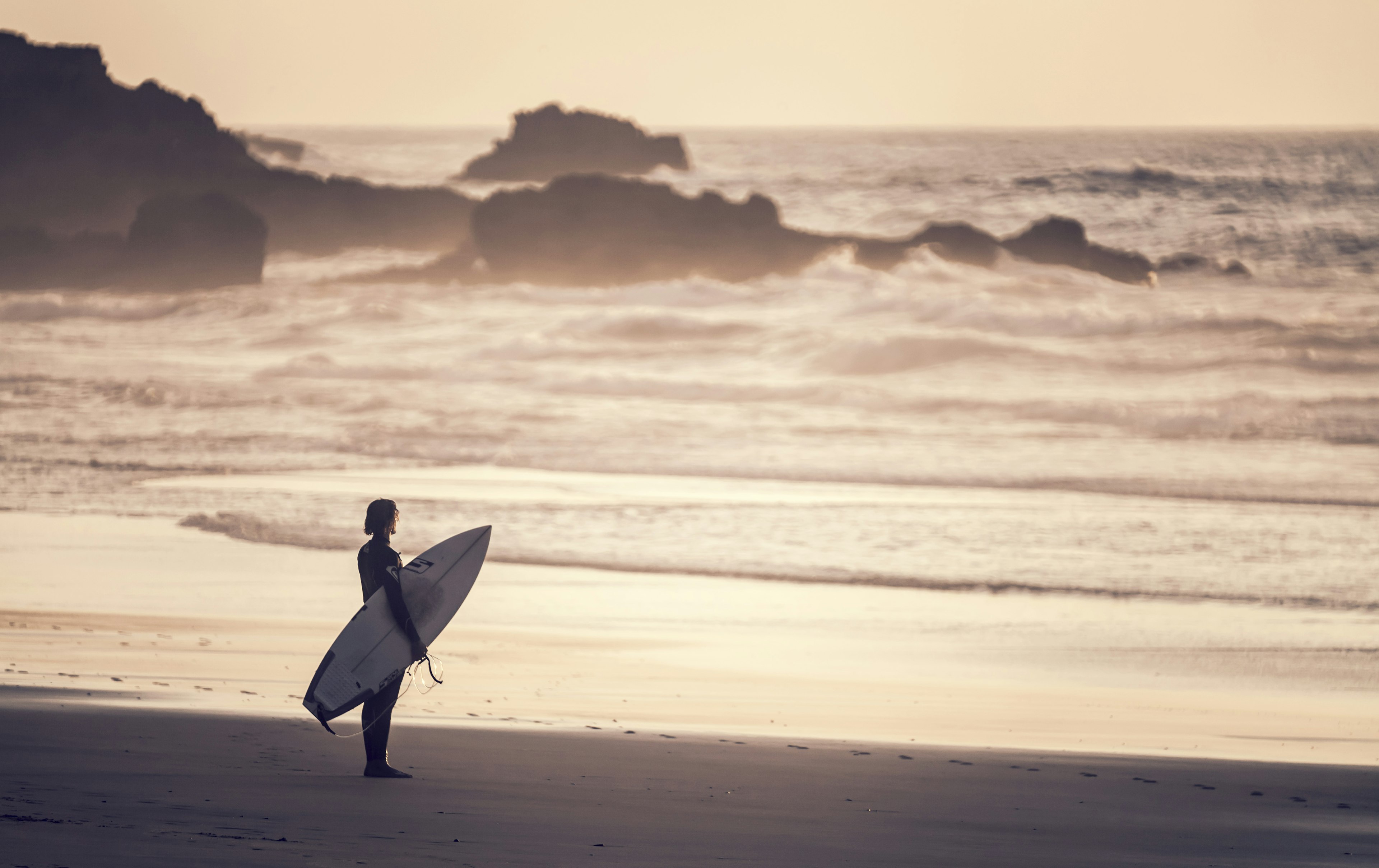 A surfer looks at the waves at Praia do Castelejo, Algarve