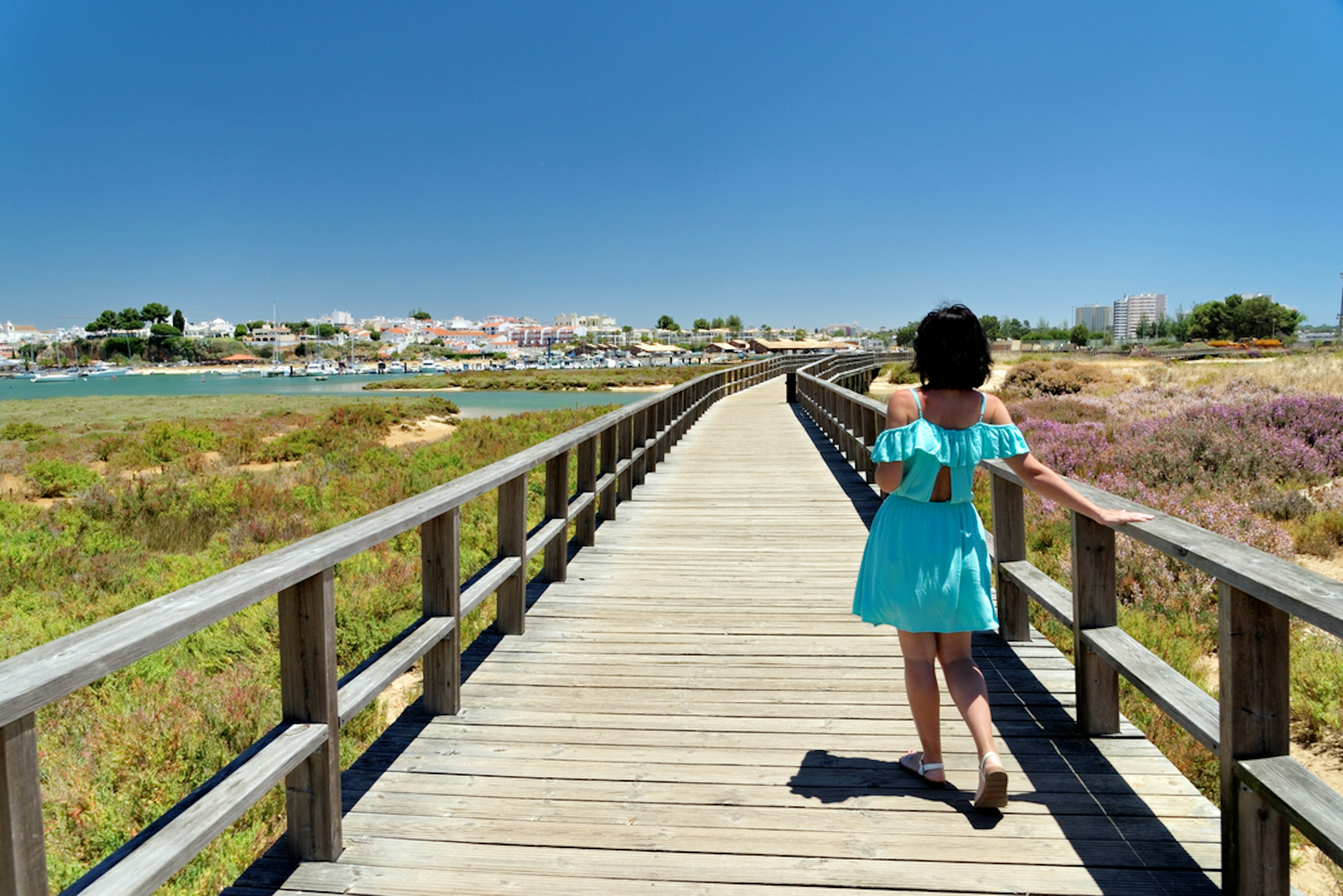 A woman walks along a boardwalk through a wildlife reserve