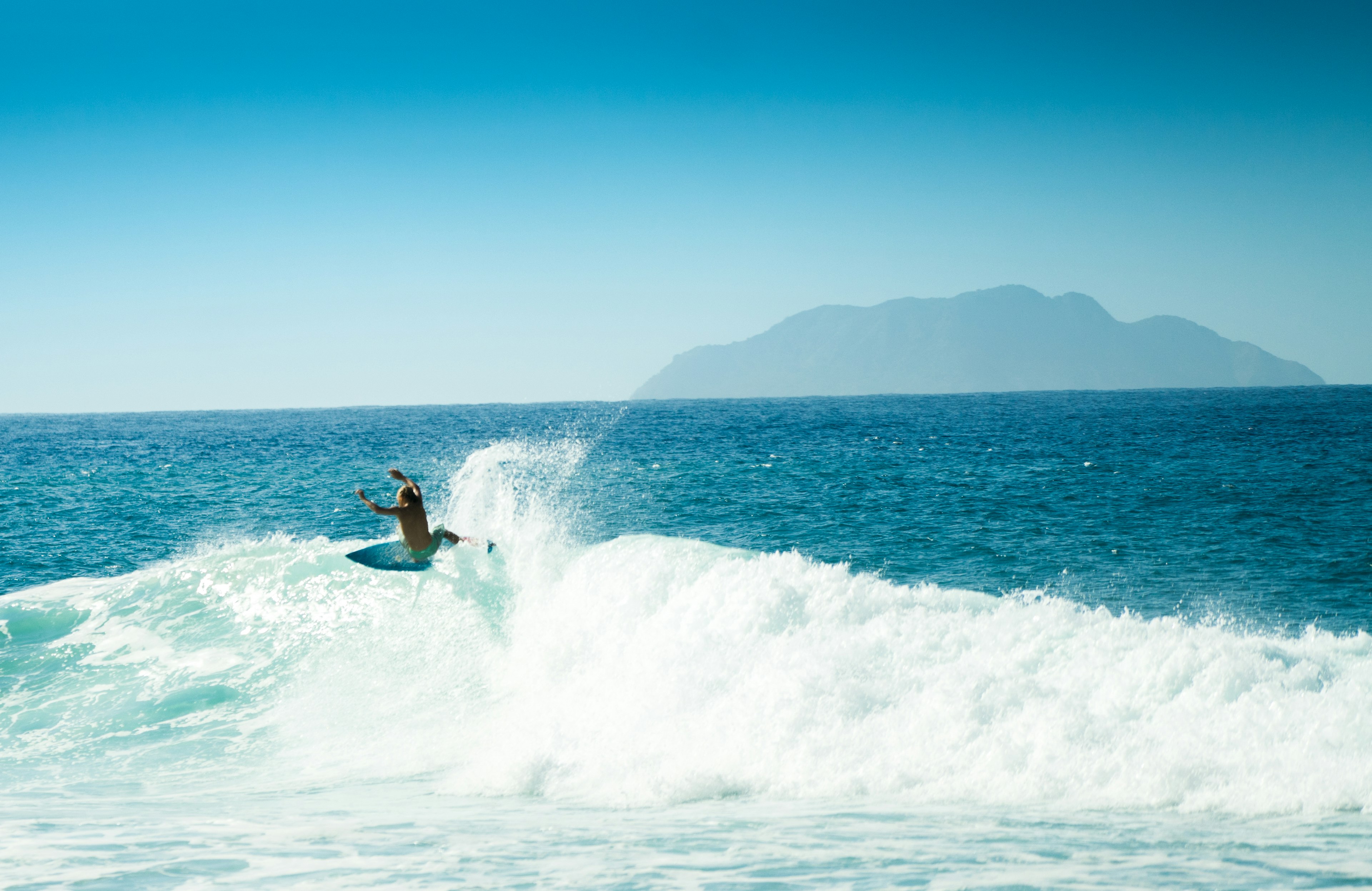 A surfer is silhouetted as they lift off the top of a wave in Rincon, Puerto Rico