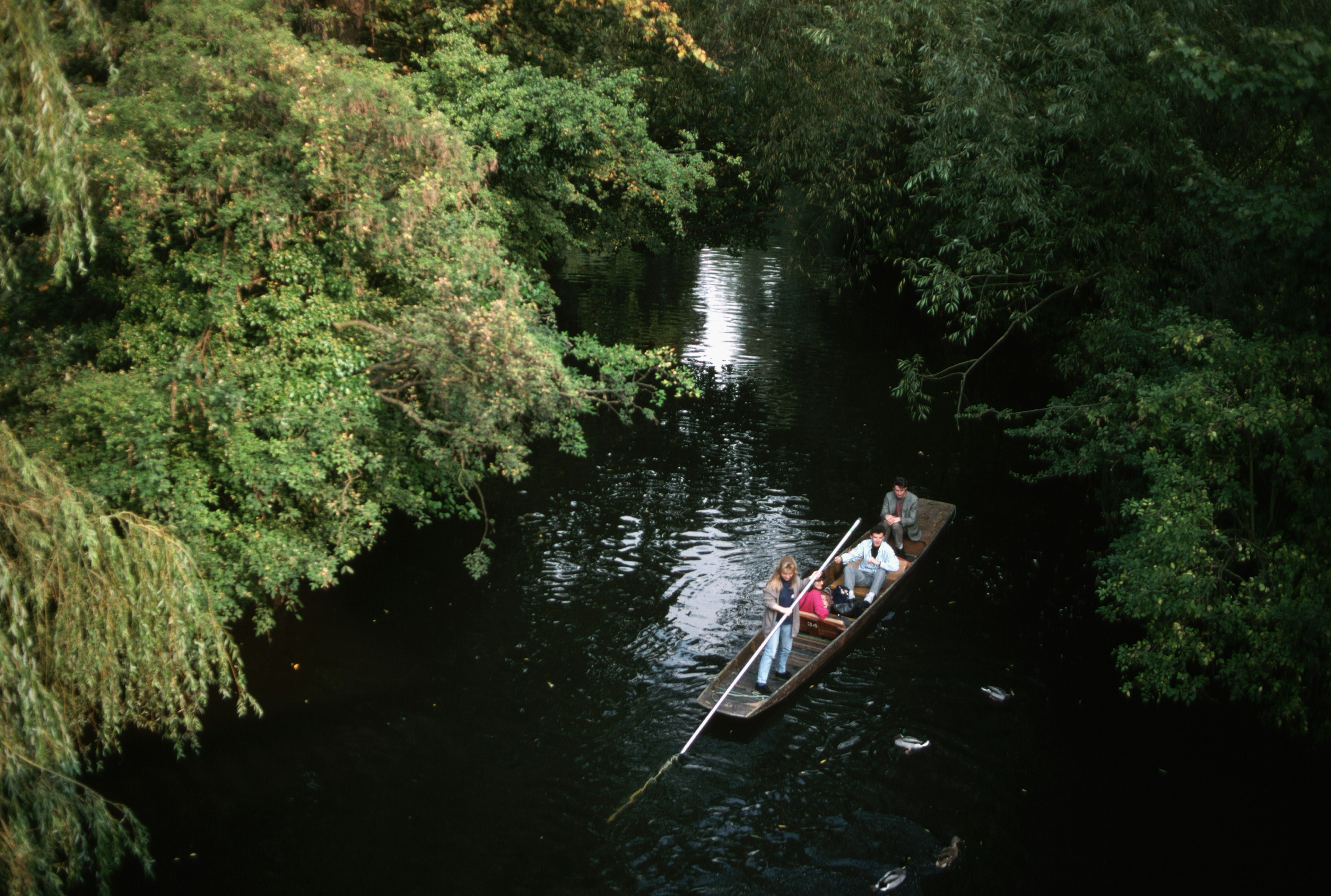 A view looking down on a group of people punting on the River Thames in Oxford.