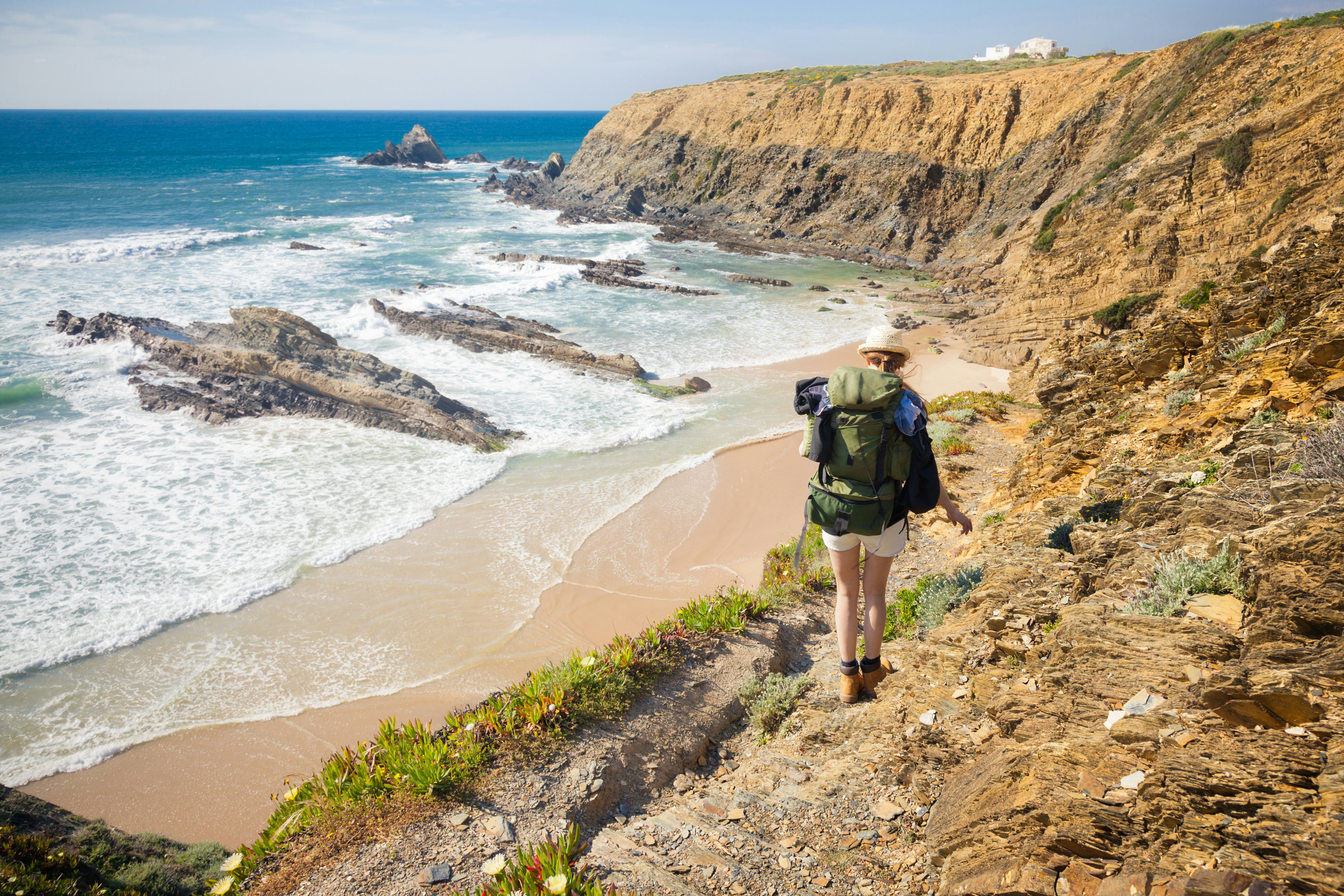 A female hiker with a large backpack hikes along a coast.