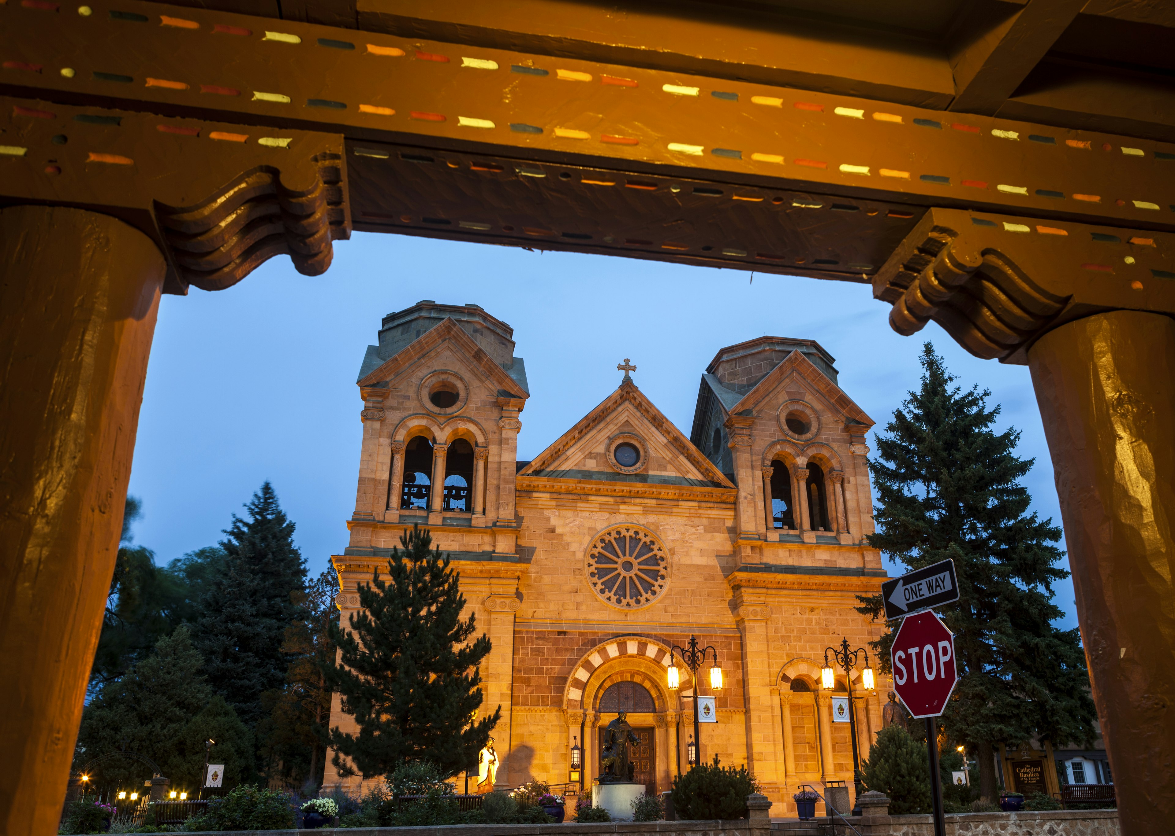 A view of the grand Cathedral Basilica Of Saint Francis in Santa Fe, framed neatly by a stone structure in the foreground.