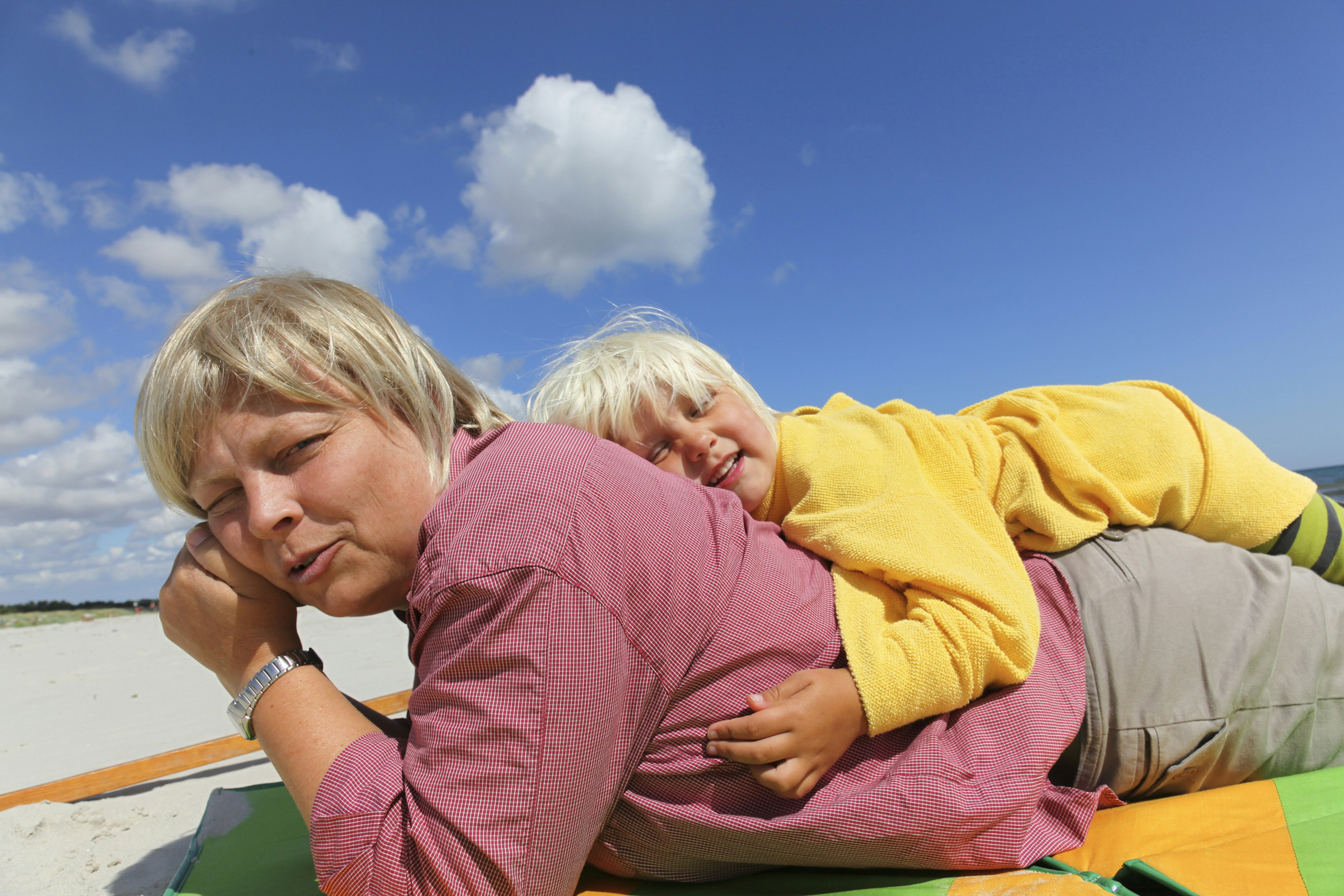 Mother and daughter laying on the sandy beach in Sandhammaren, Sweden