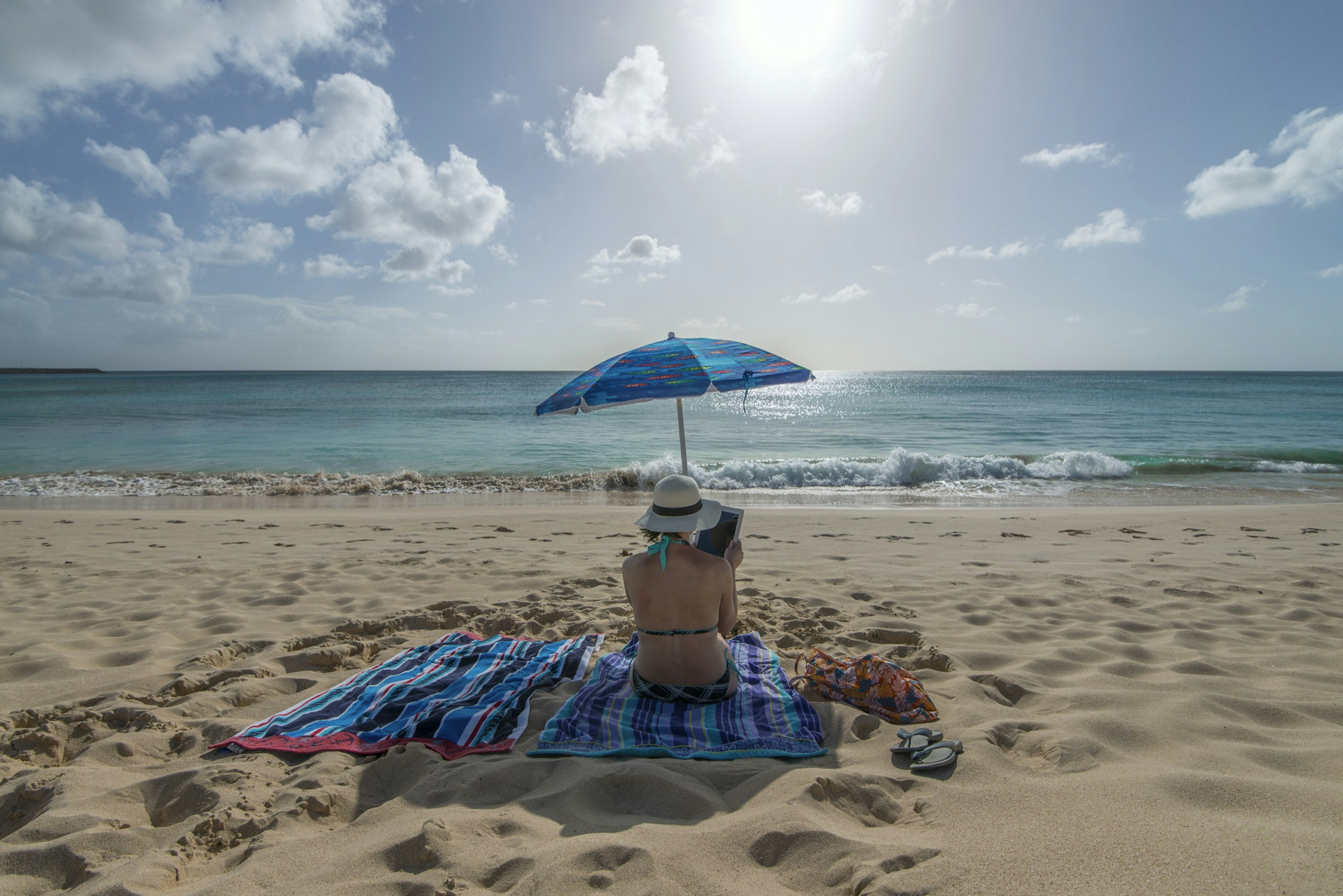 Woman uses digital tablet on uncrowded beach