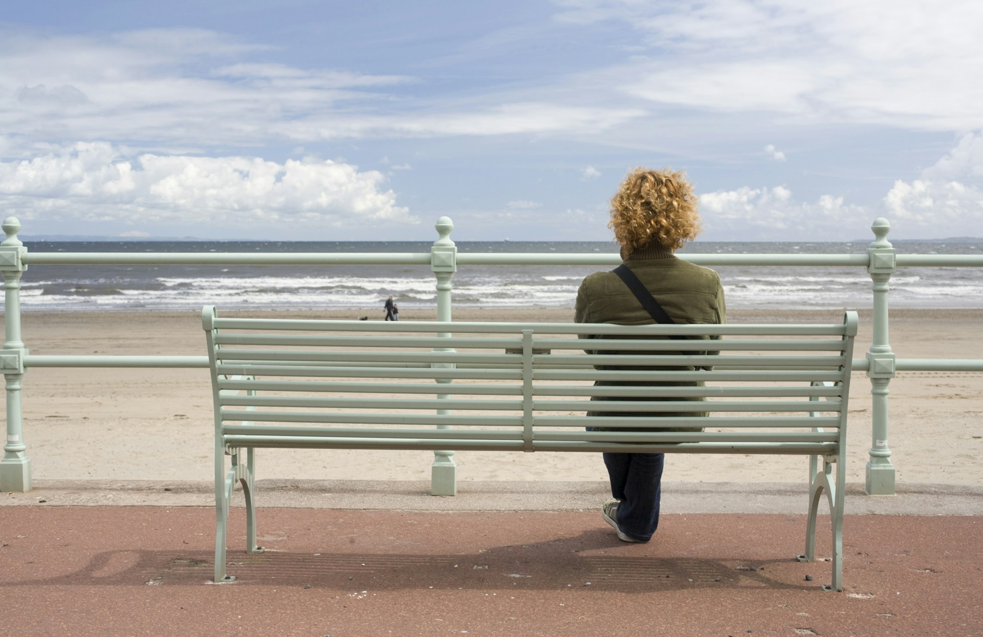 A woman sitting at a beach on the seafront near Edinburgh.