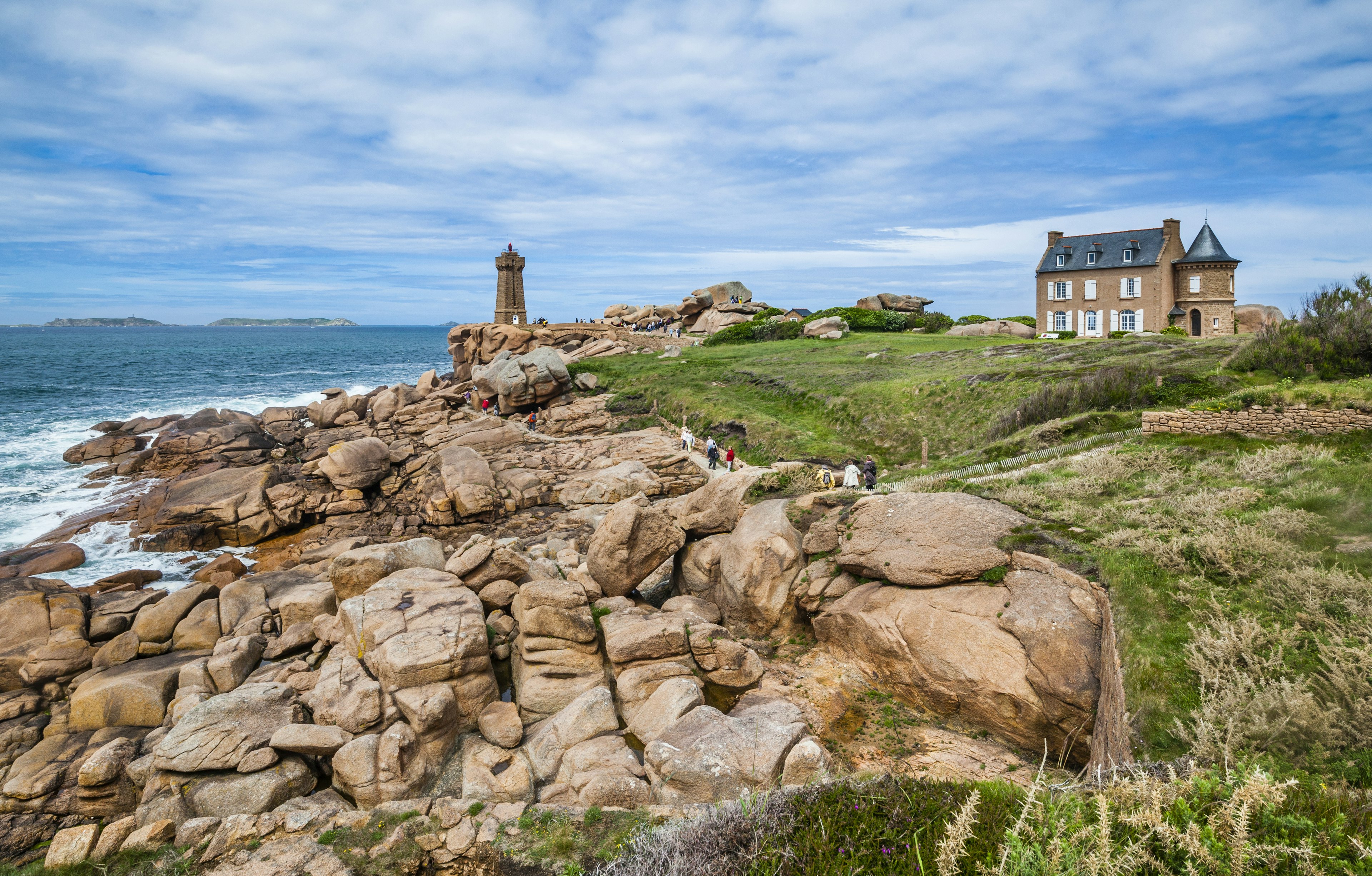 Waves crashing on a pink granite coast Sentier des Douaniers and a view of the Ploumanac'h lighthouse