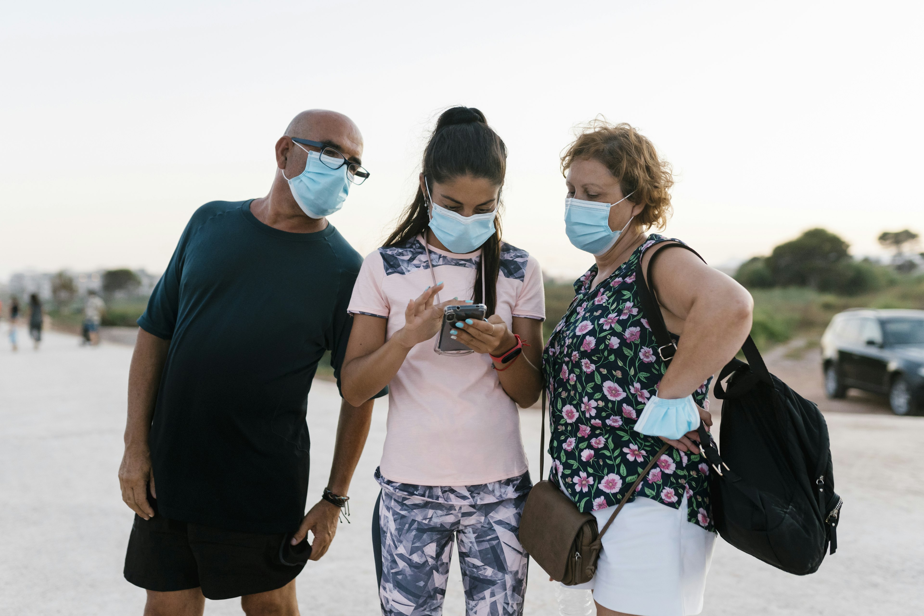 Woman using phone while standing by senior man and woman on road