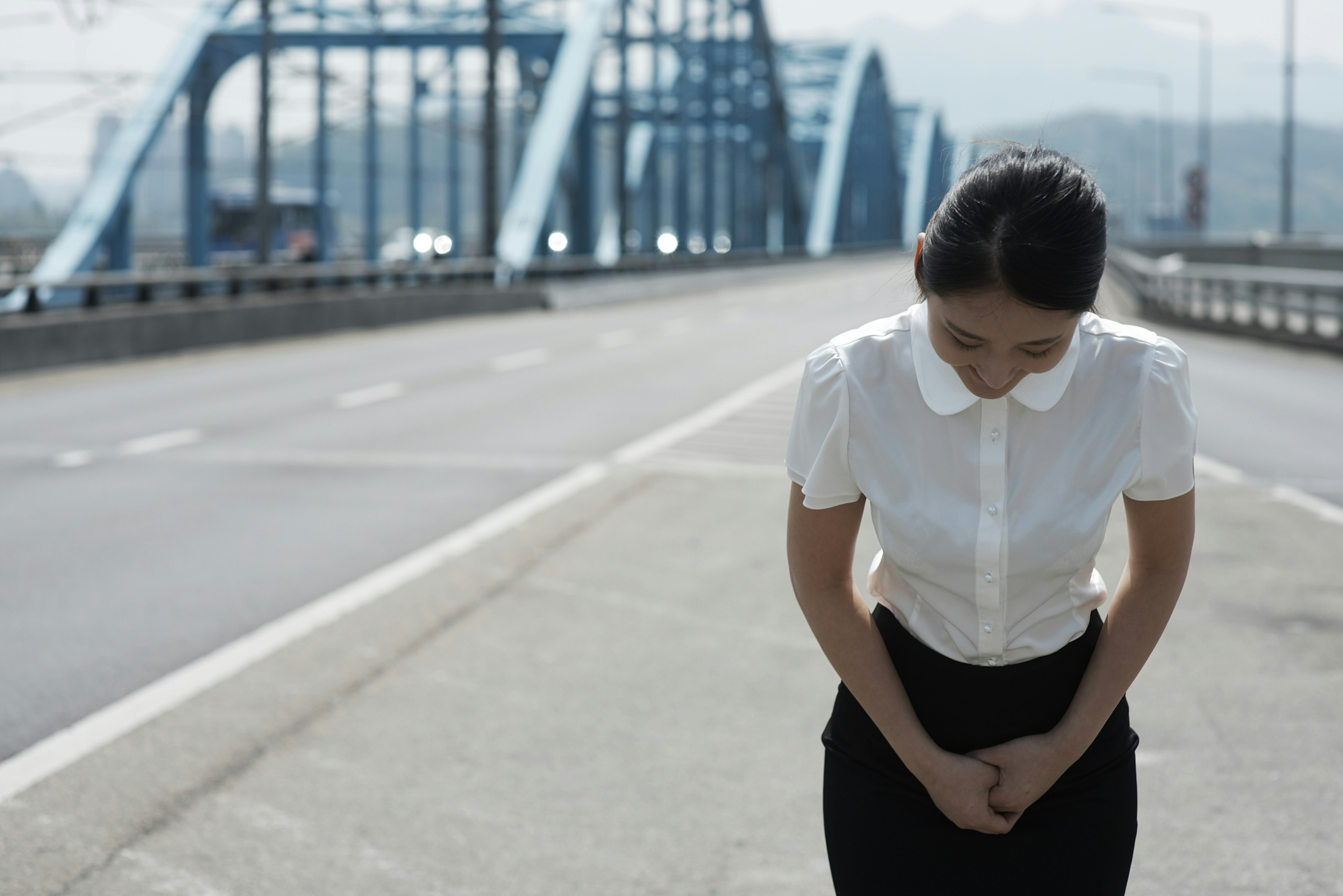 A woman in business attire bows on bridge in Gangnam, Seoul, South Korea