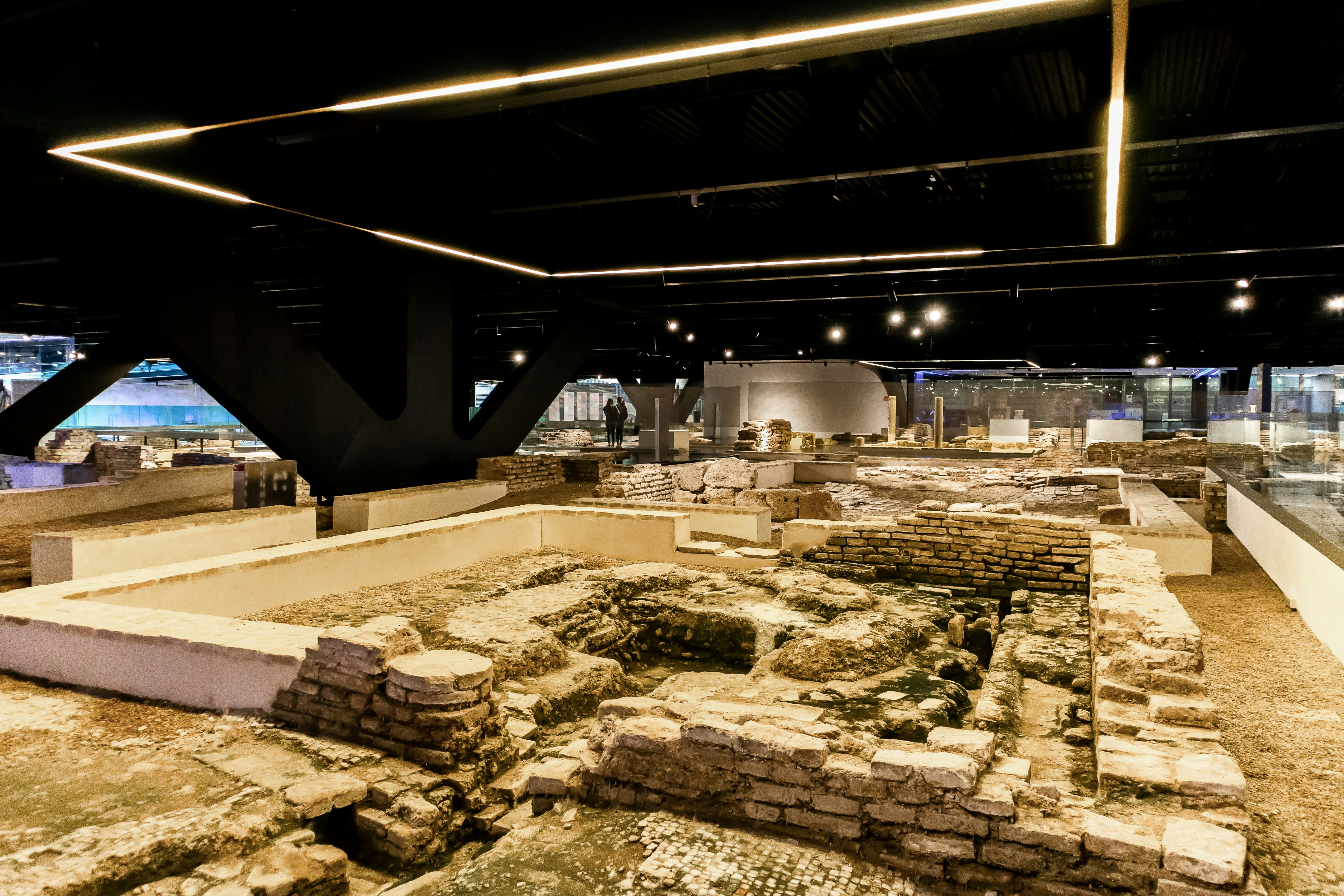 An archaeological museum with ruins lining the ground and visitors looking on from walkways