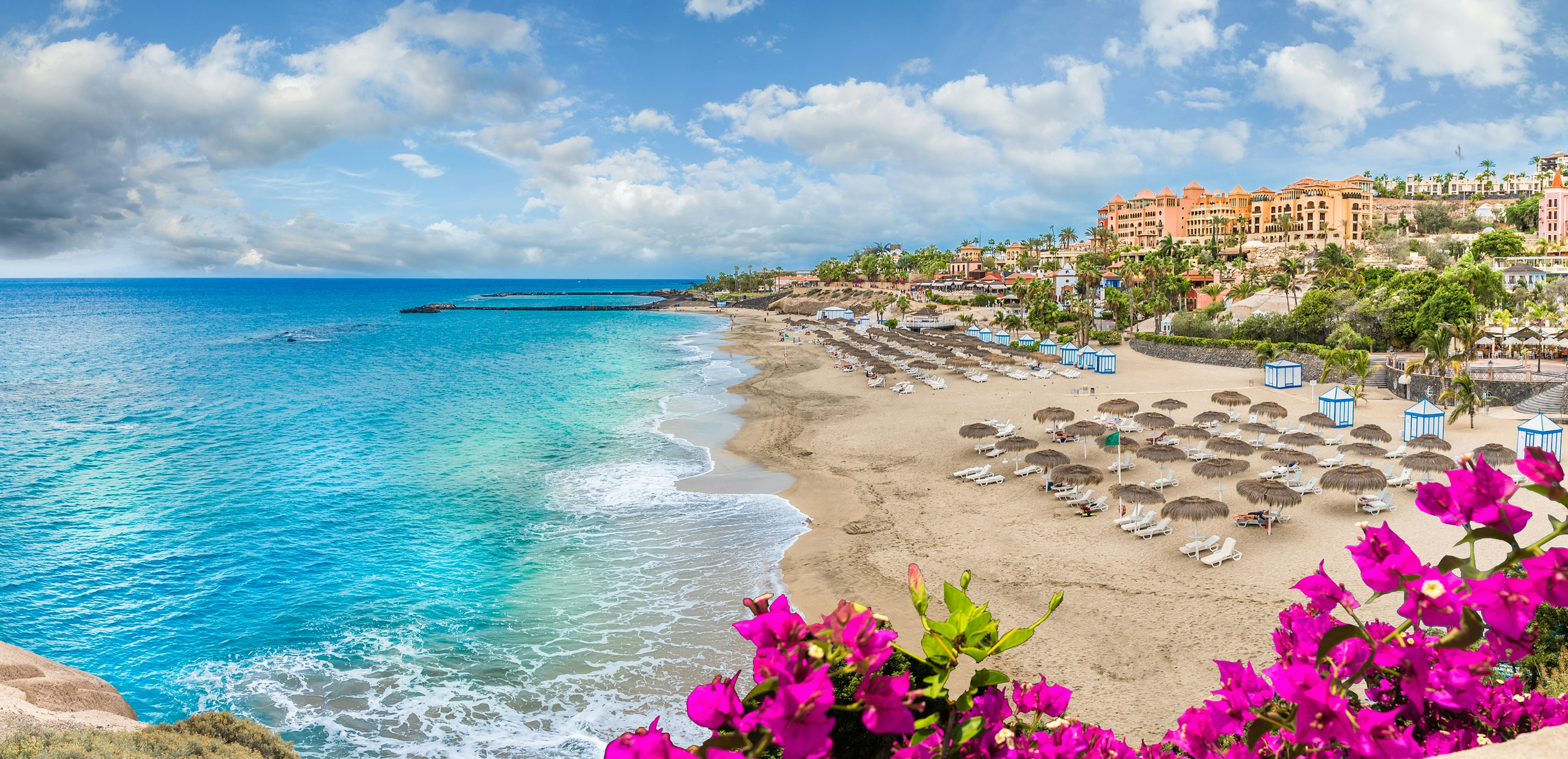 A clean beach lined with sunloungers and shades, and backed by restaurants and bars