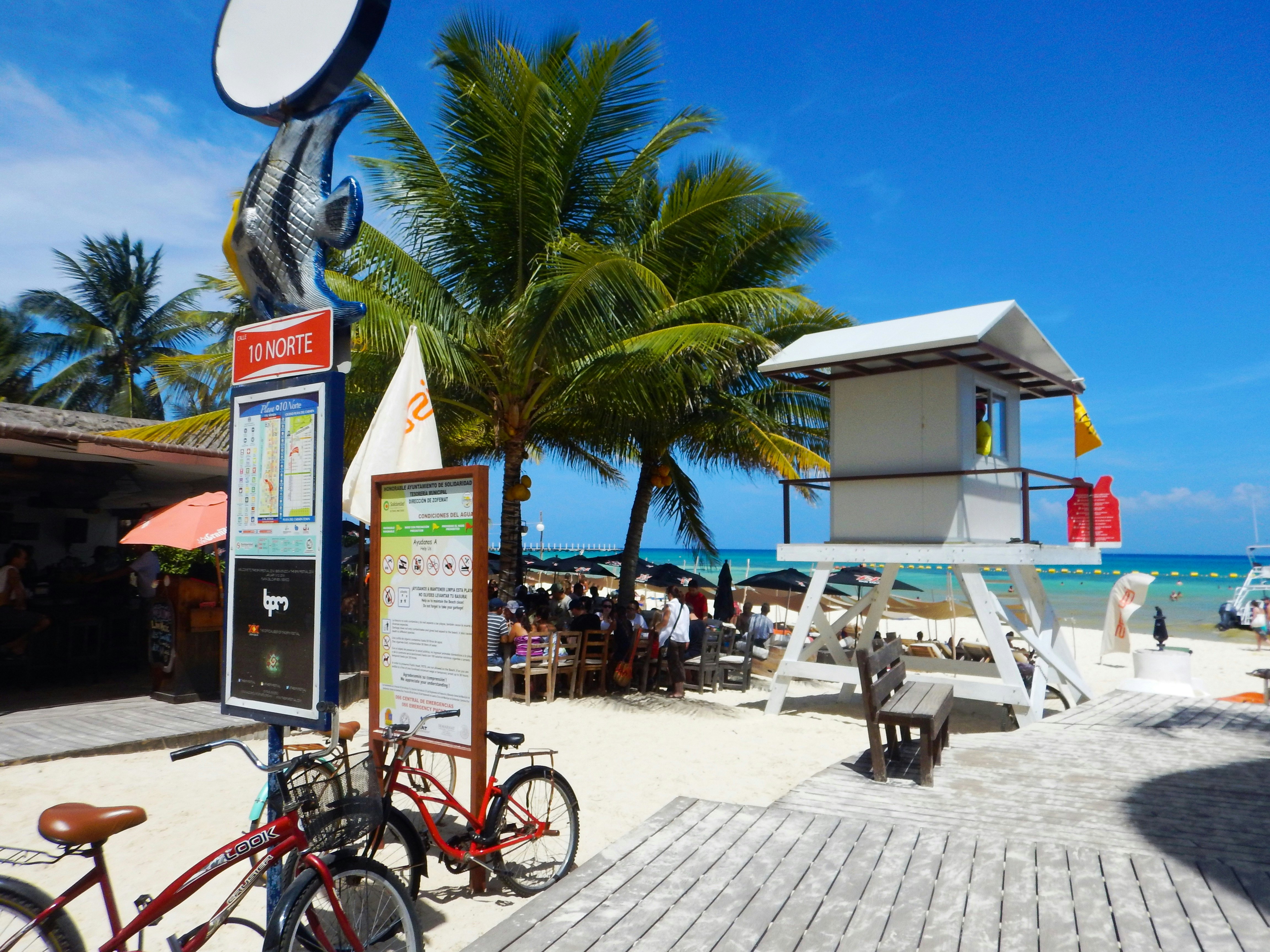 A pair of bicycles parked by a lifeguard station on a boardwalk by the beach in Playa del Carmen, Quintana Roo, Mexico, with the blue Caribbean Sea beyond