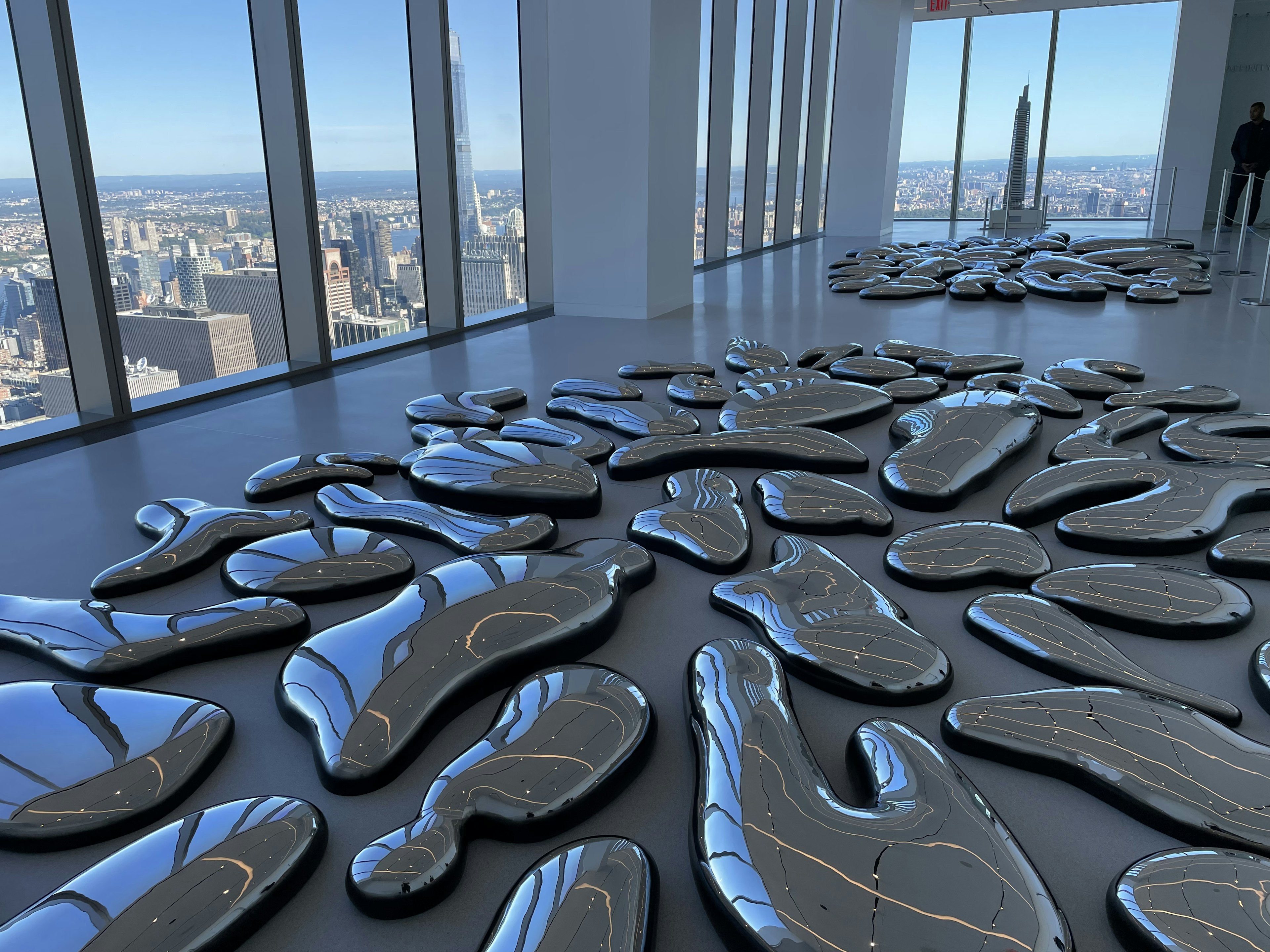 An art exhibit of metallic shapes with views of the Manhattan skyline