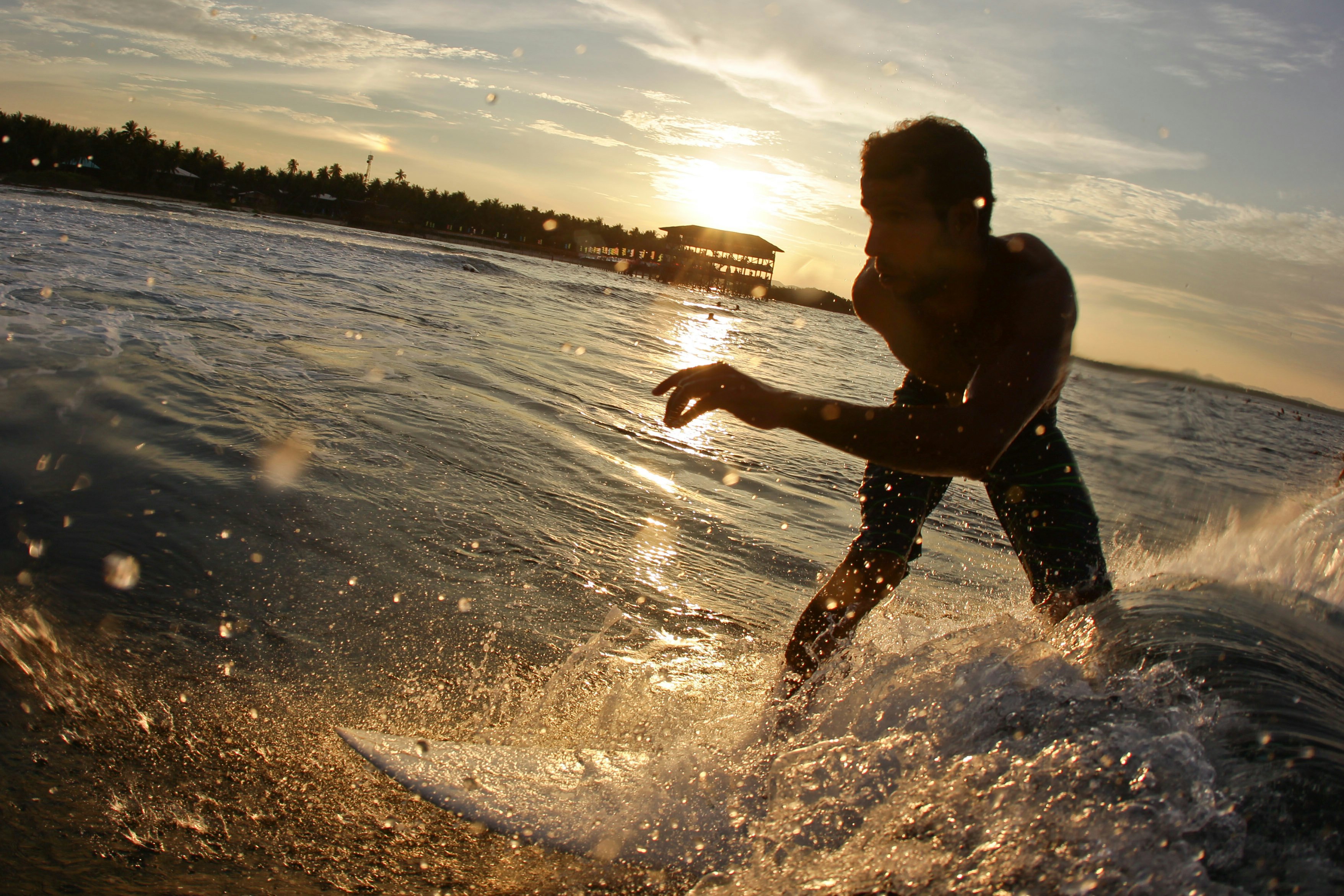 A surfer rides a wave in the Cloud 9 break at sunset in Siargao, the Philippines