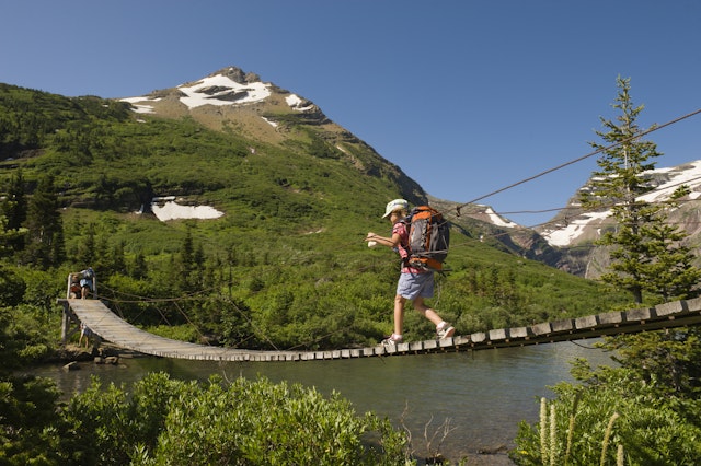 A young girl hikes over a suspension bridge in Glacier National Park, Montana.