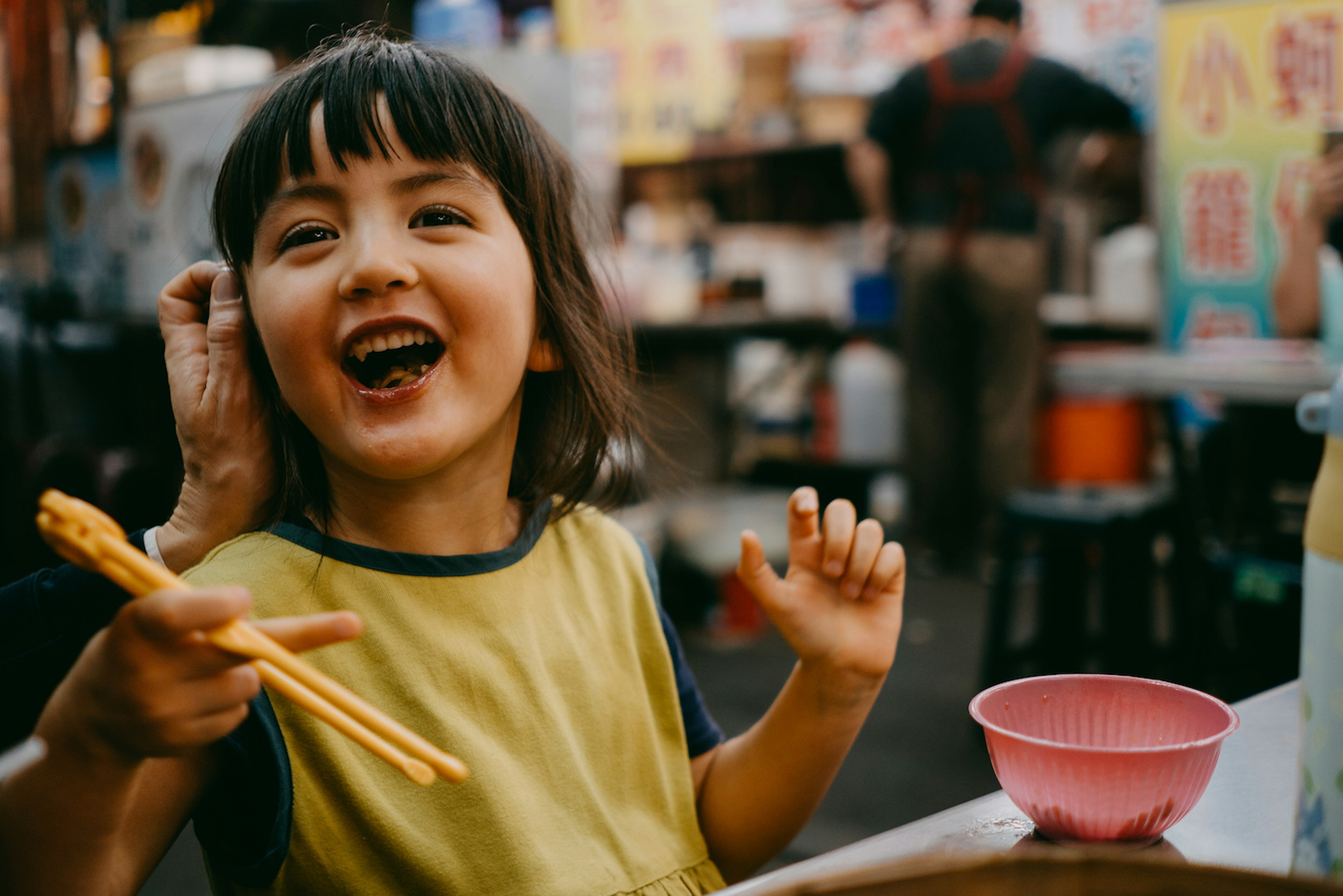 Adorable little girl enjoying xiaolongbao dumplings at a night market