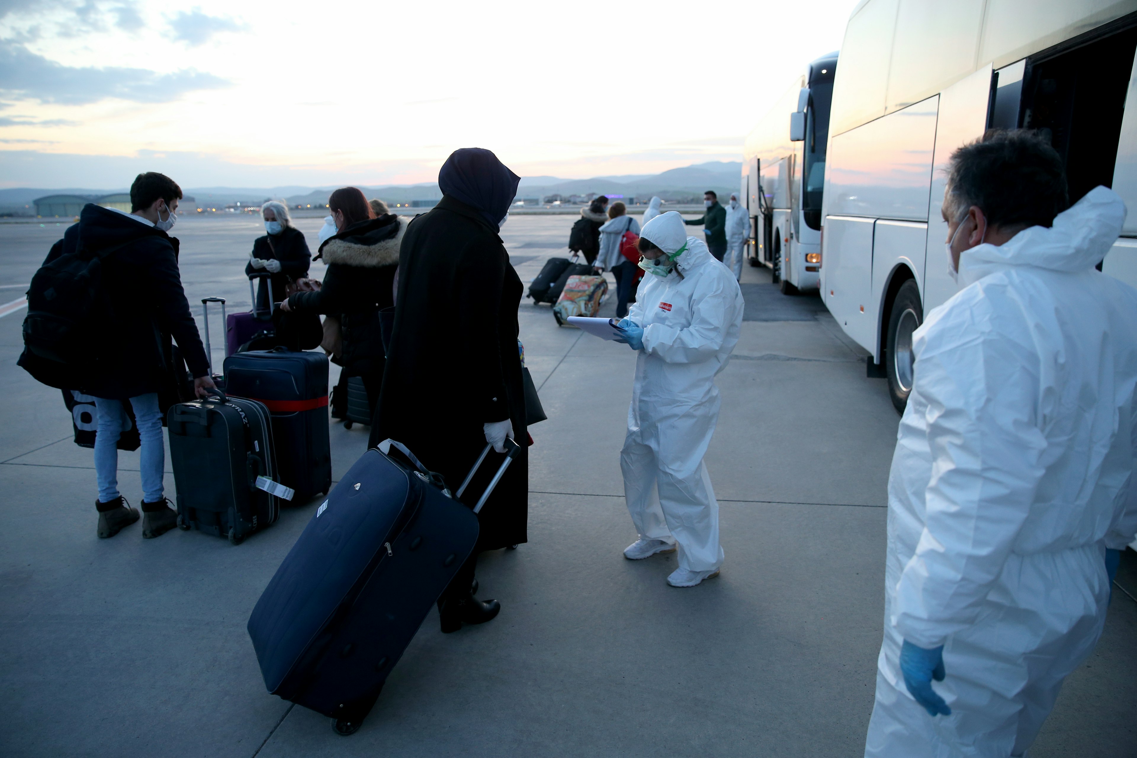 Health officials accompany Turkish passangers to leave the plane to conduct health check-up as a precaution against the coronavirus (Covid-19) pandemic at Esenboga Airport after the Turkish expats were brought from London to Ank Anadolu Agency