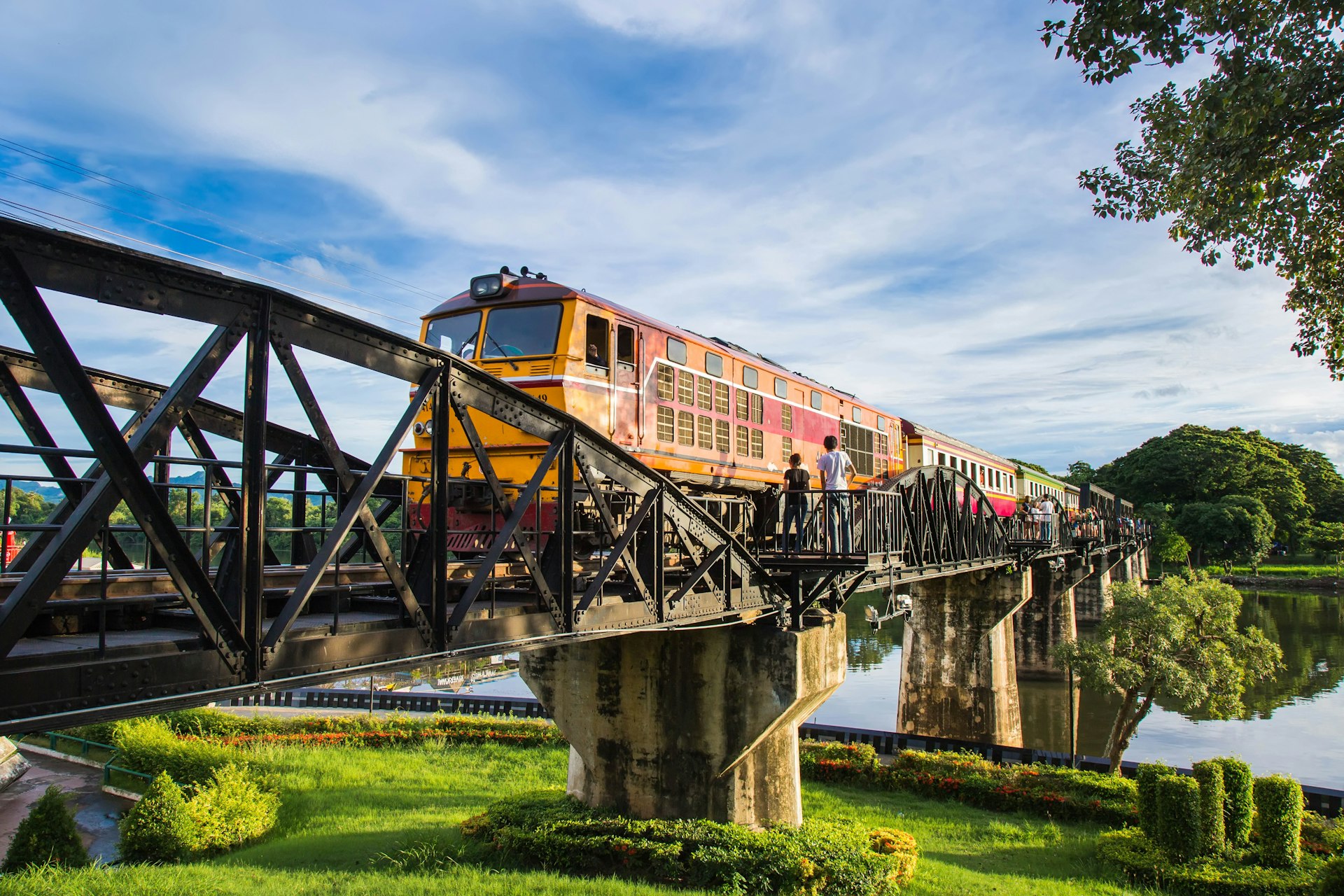 People watch a train crossing the Death Railway bridge in Kanchanburi, Thailand 