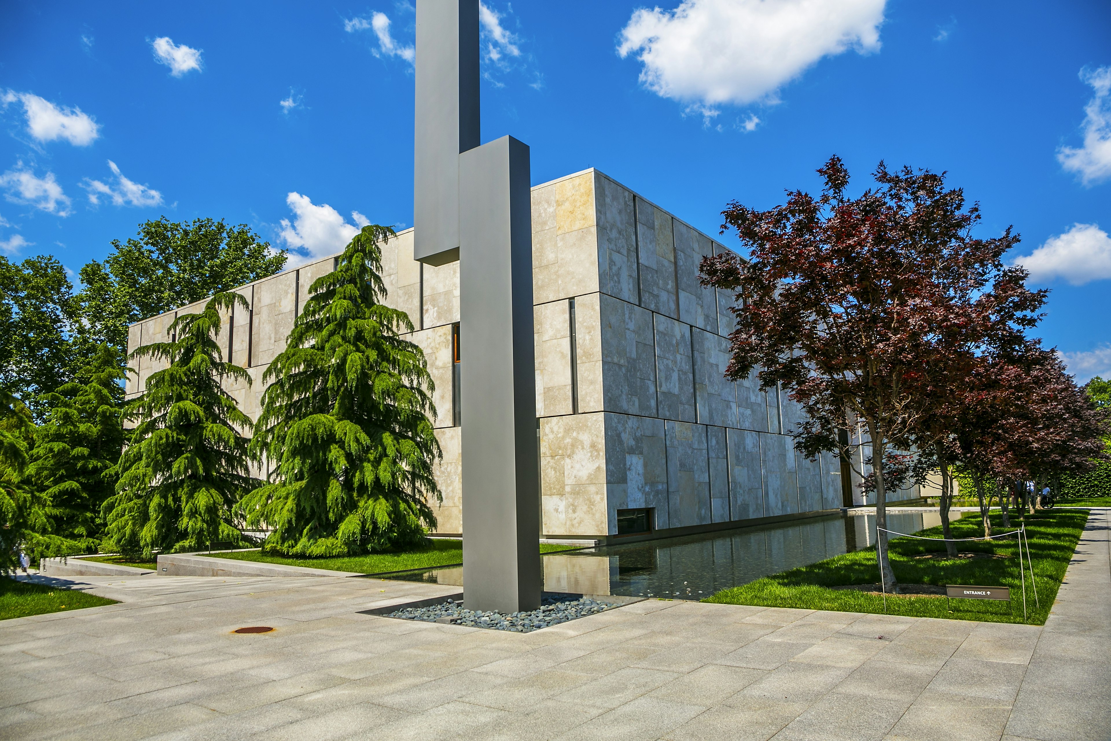 Exterior of The Barnes Foundation at Philadelphia. There's a jagged statute in front and trees surrounding the buildings.