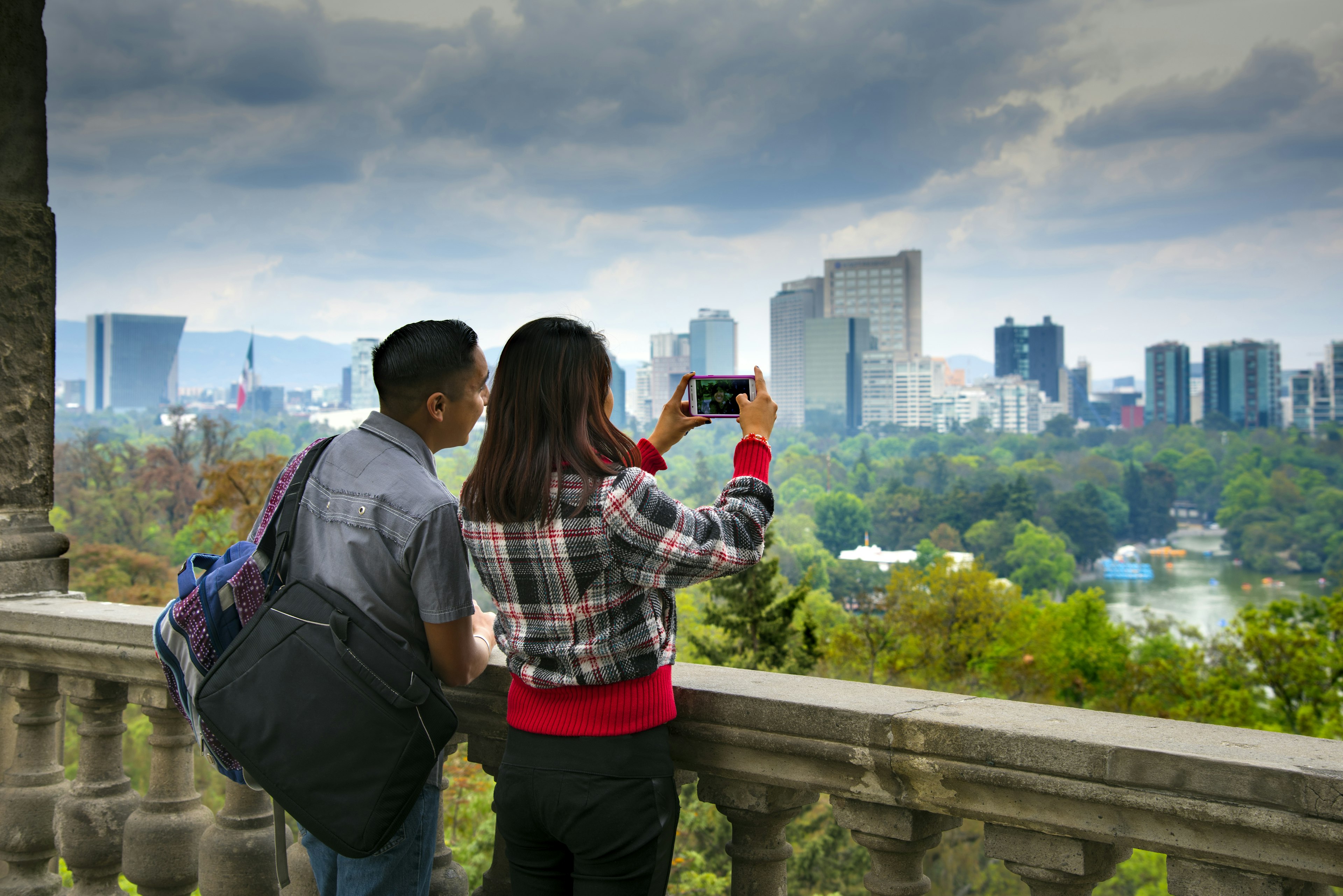 Visitors to Chapultepec Park seen from behind, taking photographs of the views of Mexico City